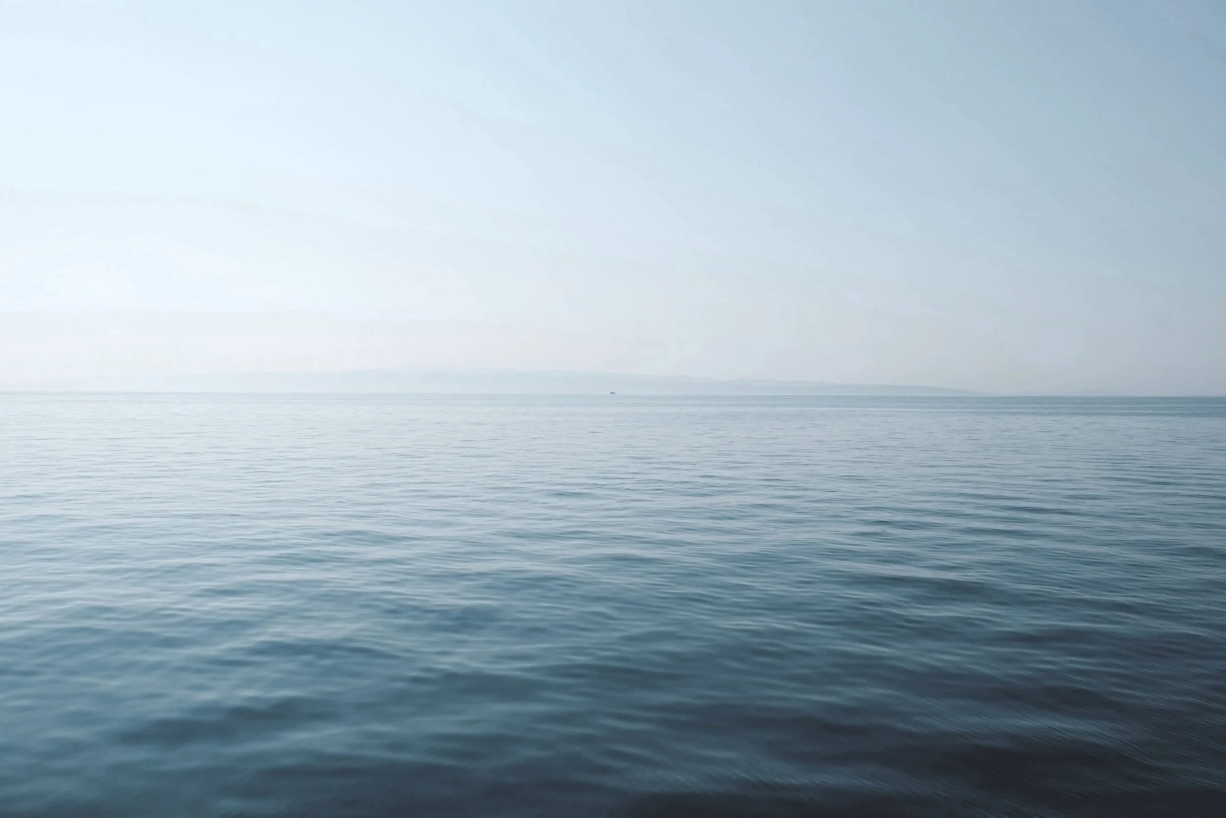 Calm ocean with gentle ripples, a distant horizon, overcast sky