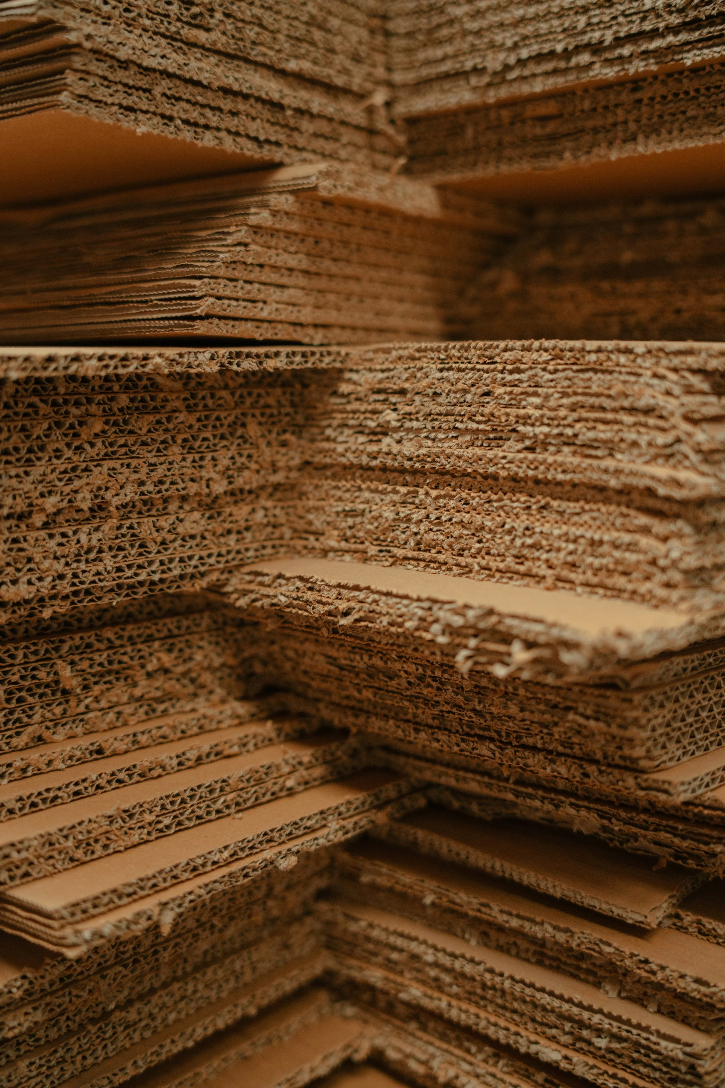 Close-up of stacked corrugated cardboard sheets, showing their wavy internal structure.