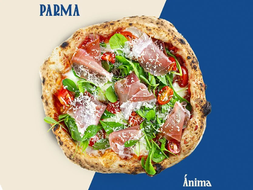 Pizza com massa grossa, presunto, tomates e folhas verdes, gratinada com queijo ralado