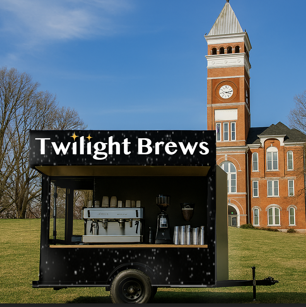 A black coffee cart named 'Twilight Brews' with a coffee machine, cups, and other equipment, set up on a grassy area in front of a large brick building with a clock tower, against a clear blue sky.