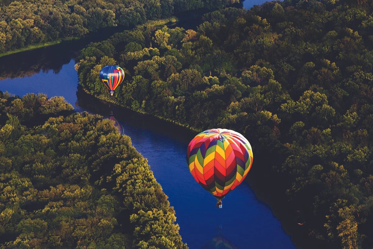 Spiedie Fest hot air balloons over river.