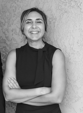 A portrait of a woman smiling looking approchable with arms crossed