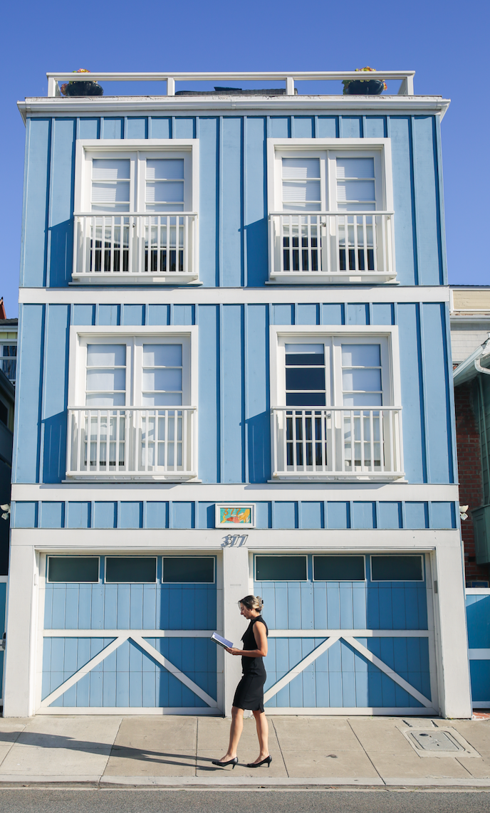 A woman wearing black dress standing at the front of a blue building