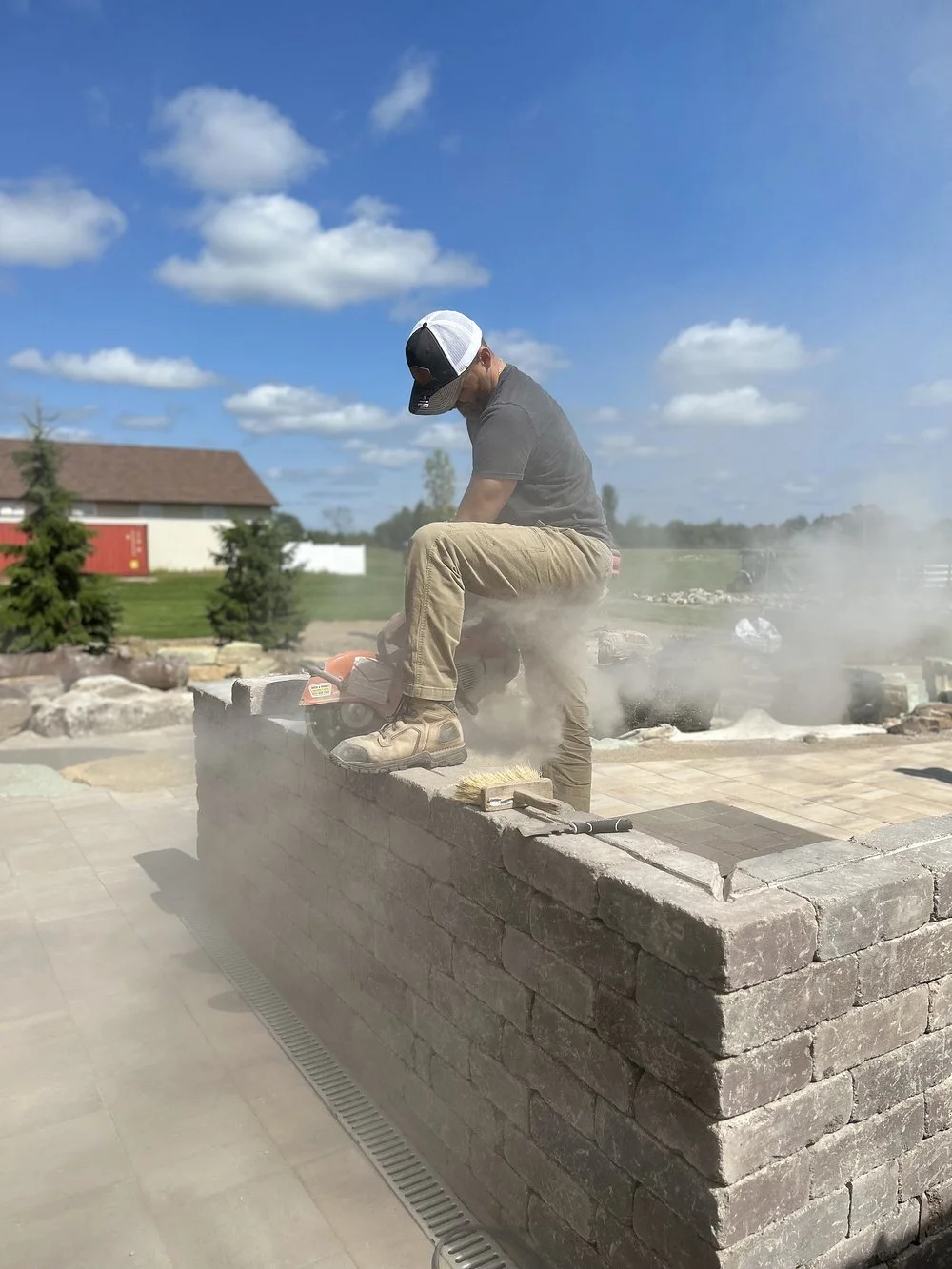 A mason cutting stone for a seating wall by Luck Lagoons