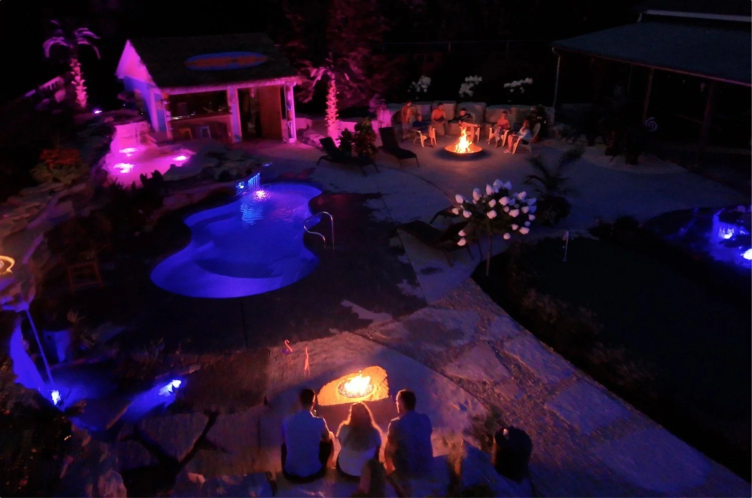 Luxury backyard pool and fire features illuminated at night by Luck Lagoons