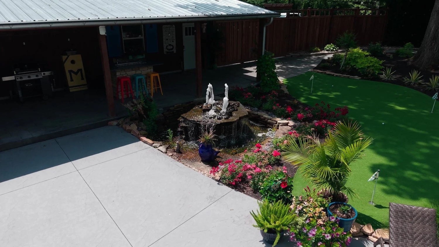 A bubbling fountain bed beside an artificial turf putting green by Luck Lagoons