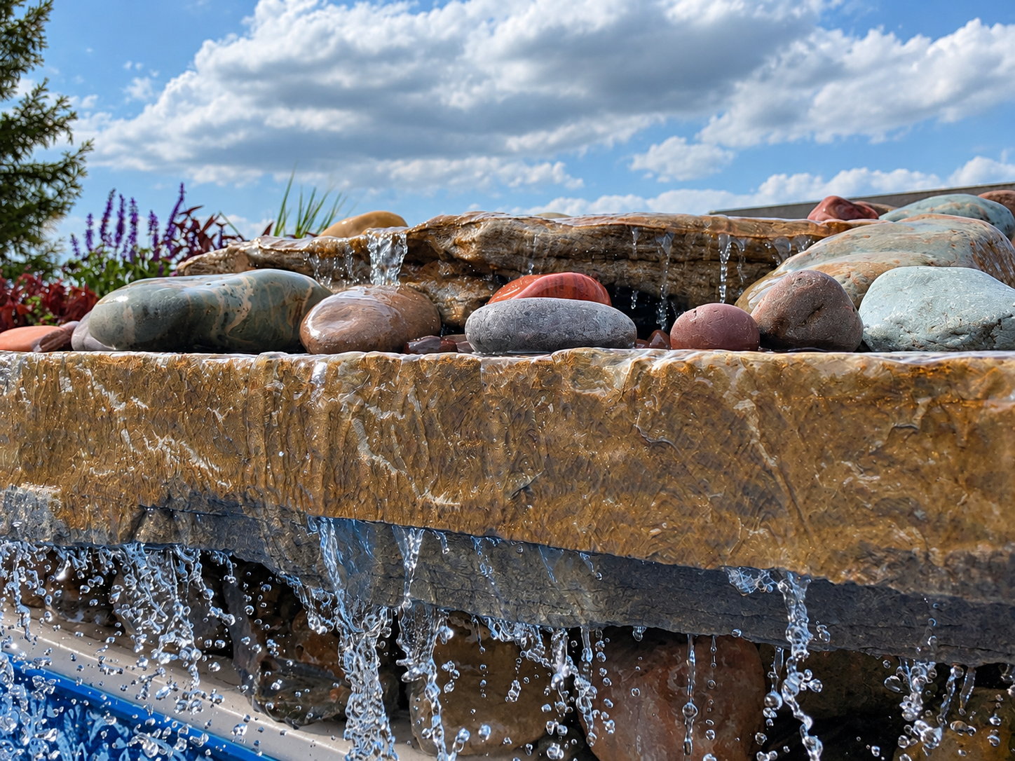 Close-up of a swimming pool edge with multi-colored rocks along the concrete border.