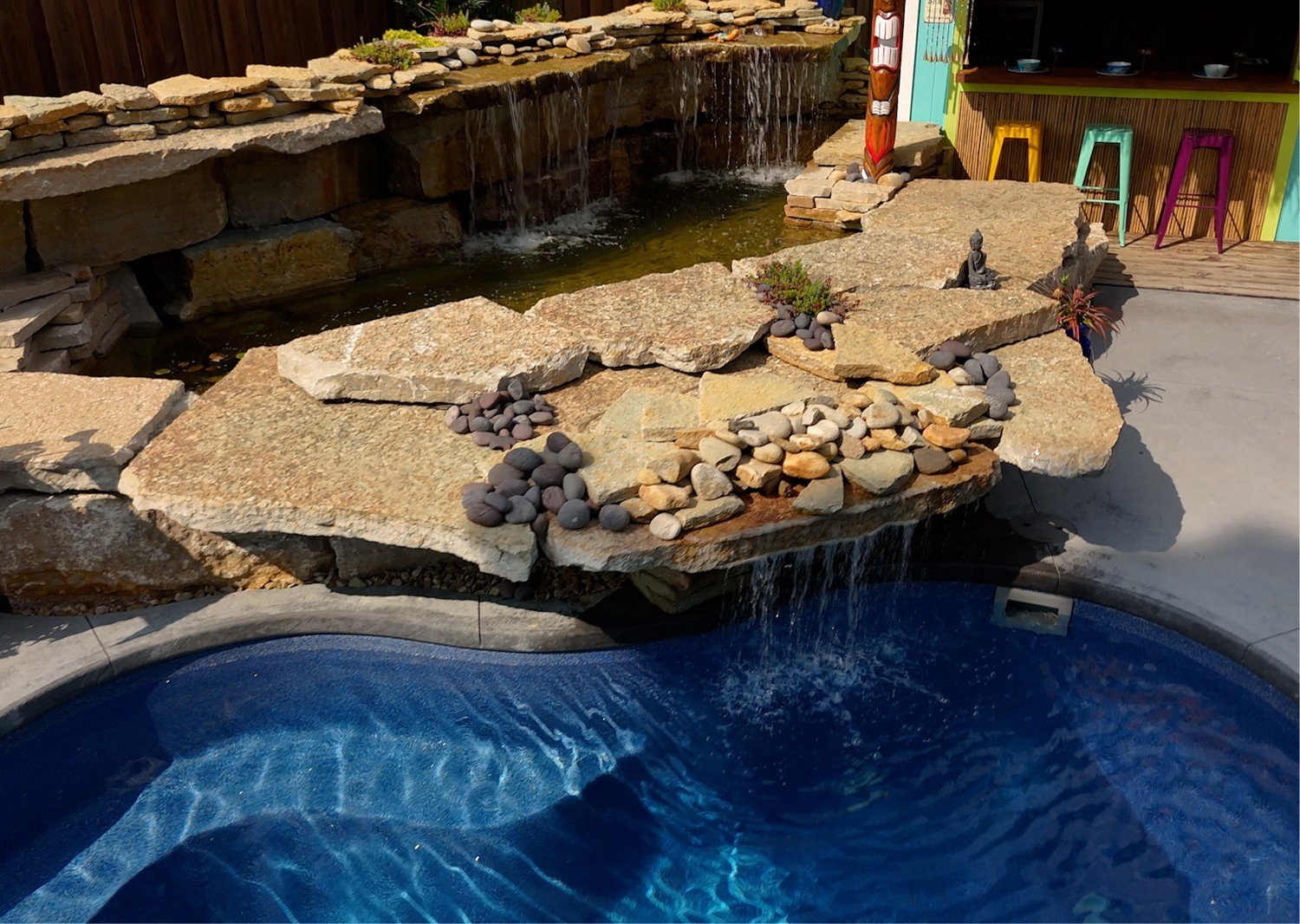 Natural stone waterfall flowing into custom pool by Luck Lagoons