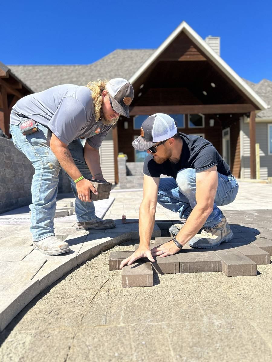 Two Luck Lagoons crew members installing a paver walkway
