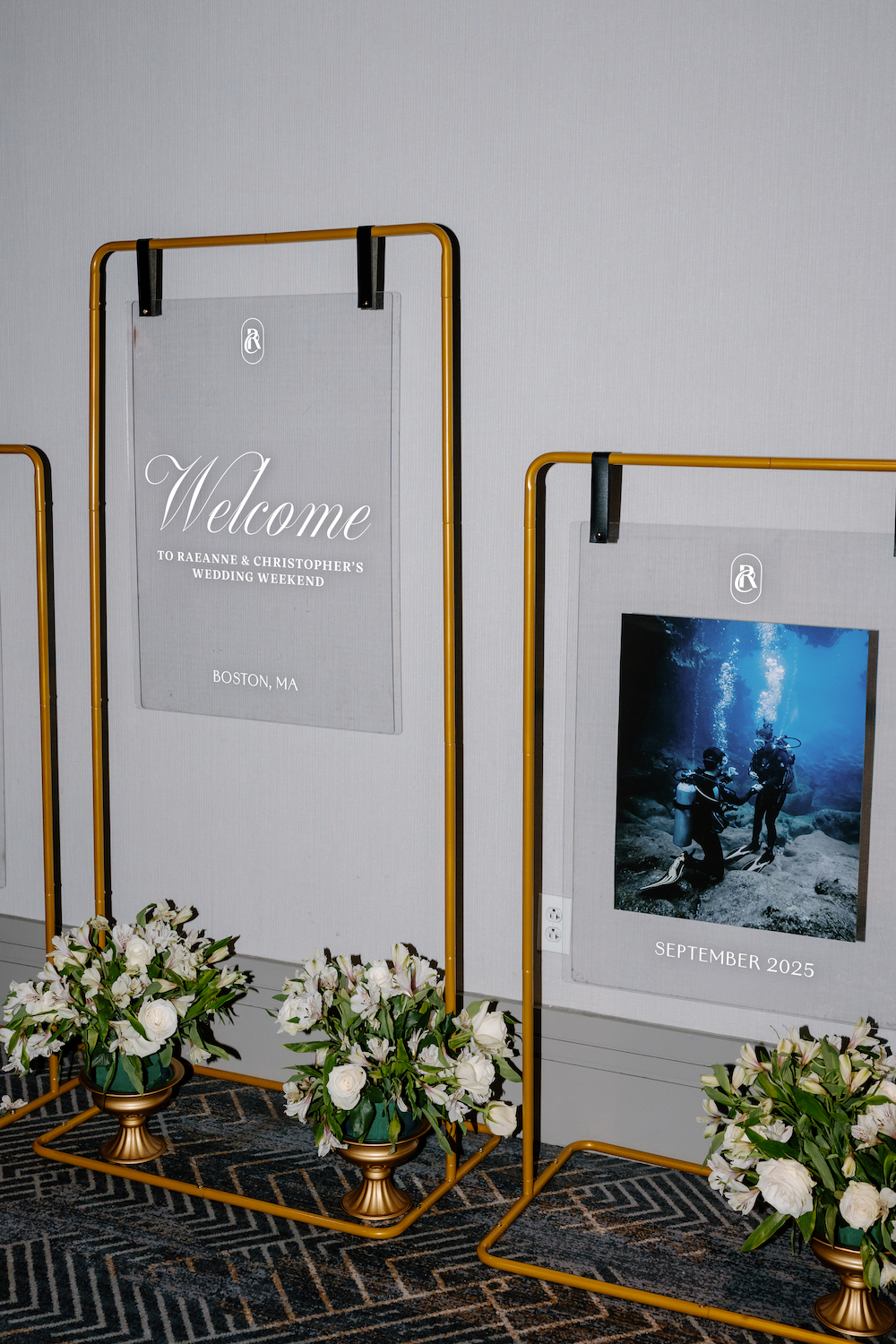 Wedding welcome sign for Raeanne and Christopher's wedding weekend in Boston, MA, with floral arrangements at the base.