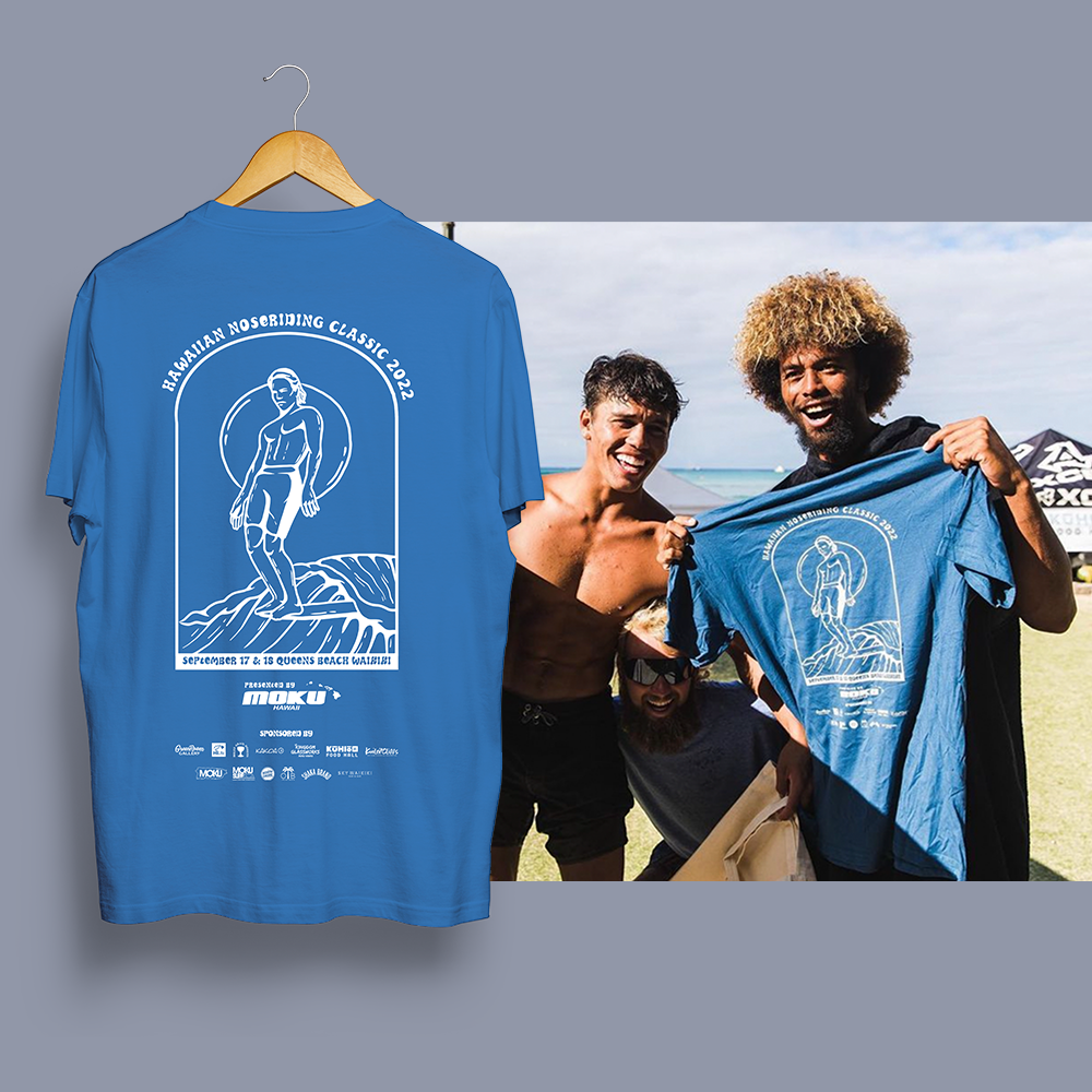 A blue T-shirt with a graphic design and event details hanging on a wooden hanger and three men at the beach holding up the T-shirt, smiling and enjoying a sunny day.