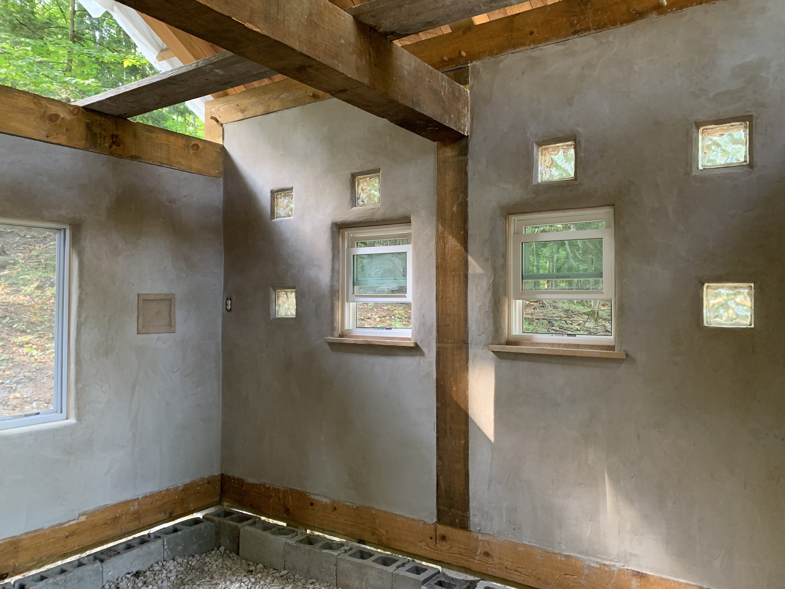 Interior earthen plaster over light-straw-clay walls in a timber frame structure