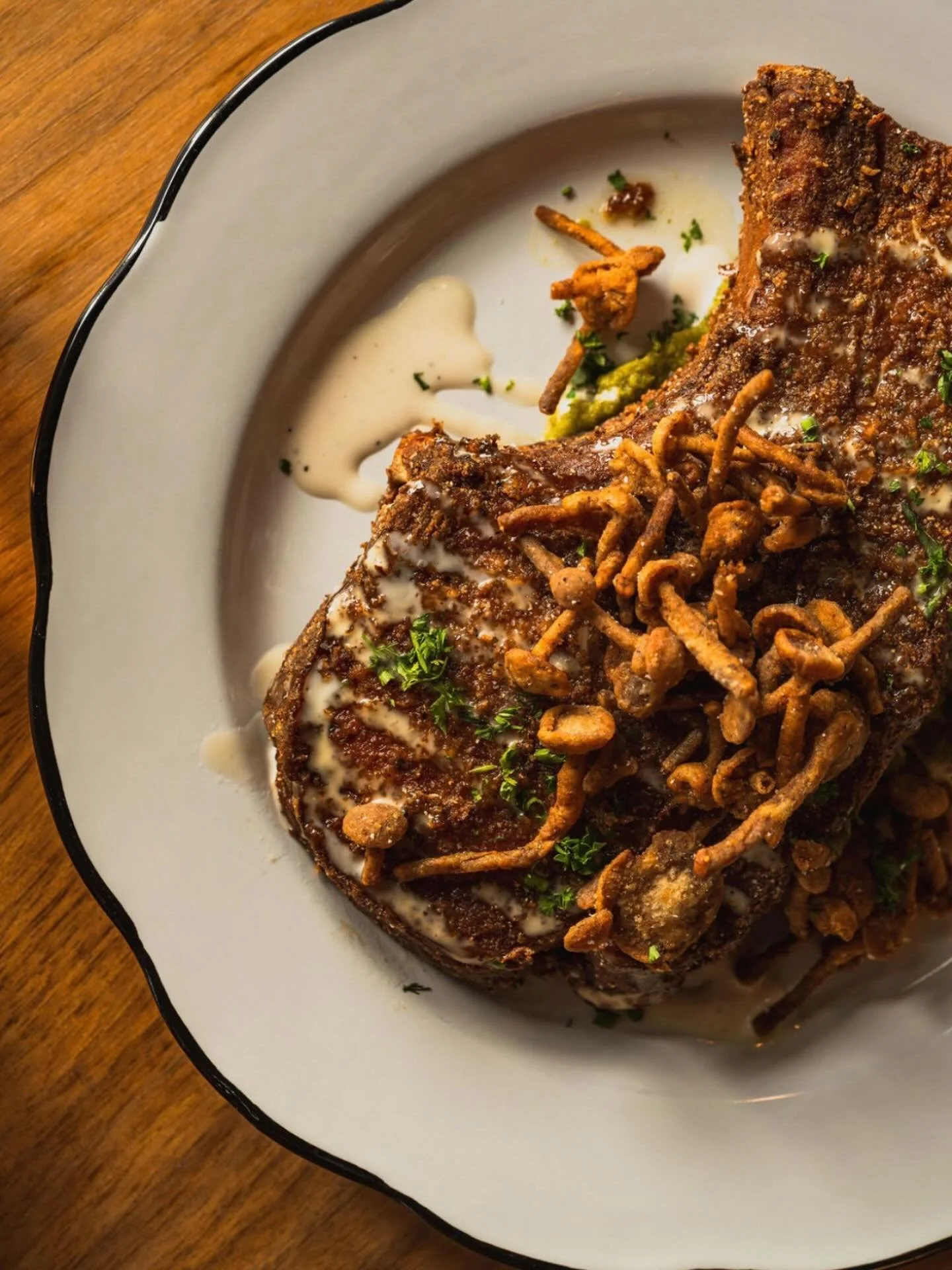 SAKURA PORK CHOP. Braised in a Calabrian chili butter. Dredged with starches and @ansonmills jimmy red cornmeal. Crisped up and served over a bed of mojo squash pur&eacute;e with Alabama BBQ and crispy enoki mushrooms from @forageandcultivate  A stun