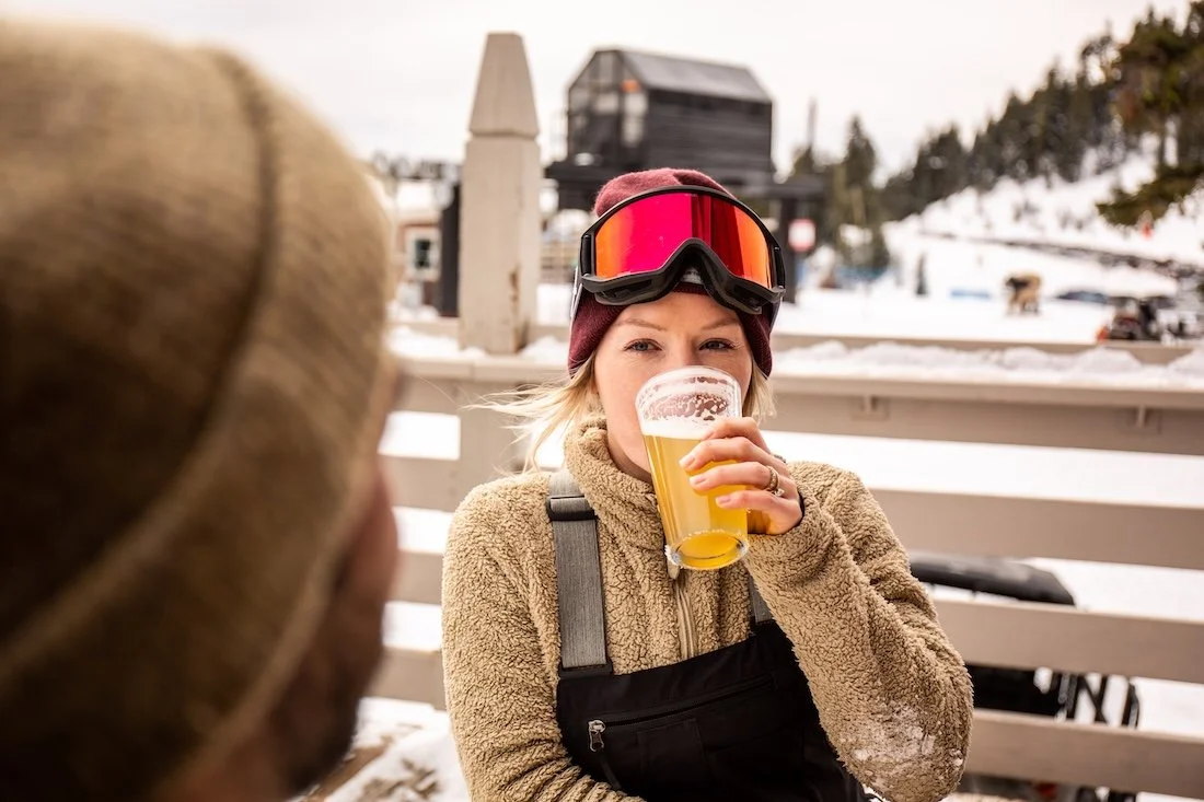 Woman drinking a beer in a hat and ski goggles at the mountain for a destination commercial photos in Bend Oregon.
