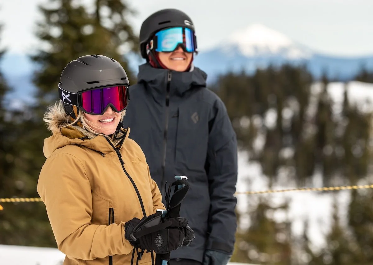Two women in ski clothes on a mountain backdrop in Bend Oregon for commercial photos.