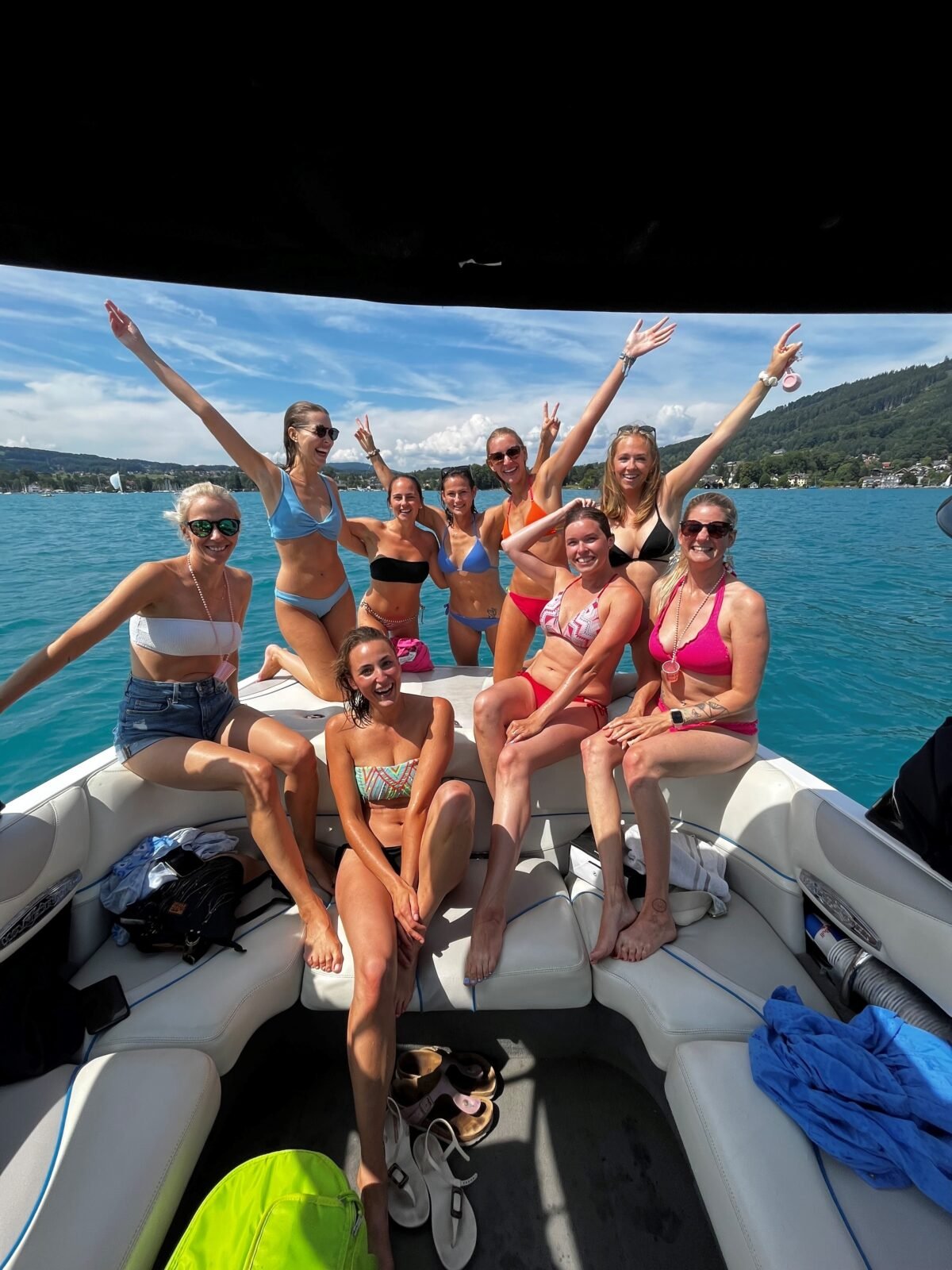 Gruppe von Frauen auf einem Boot, lachend und winkend, im Wasser und bei schönem Wetter.