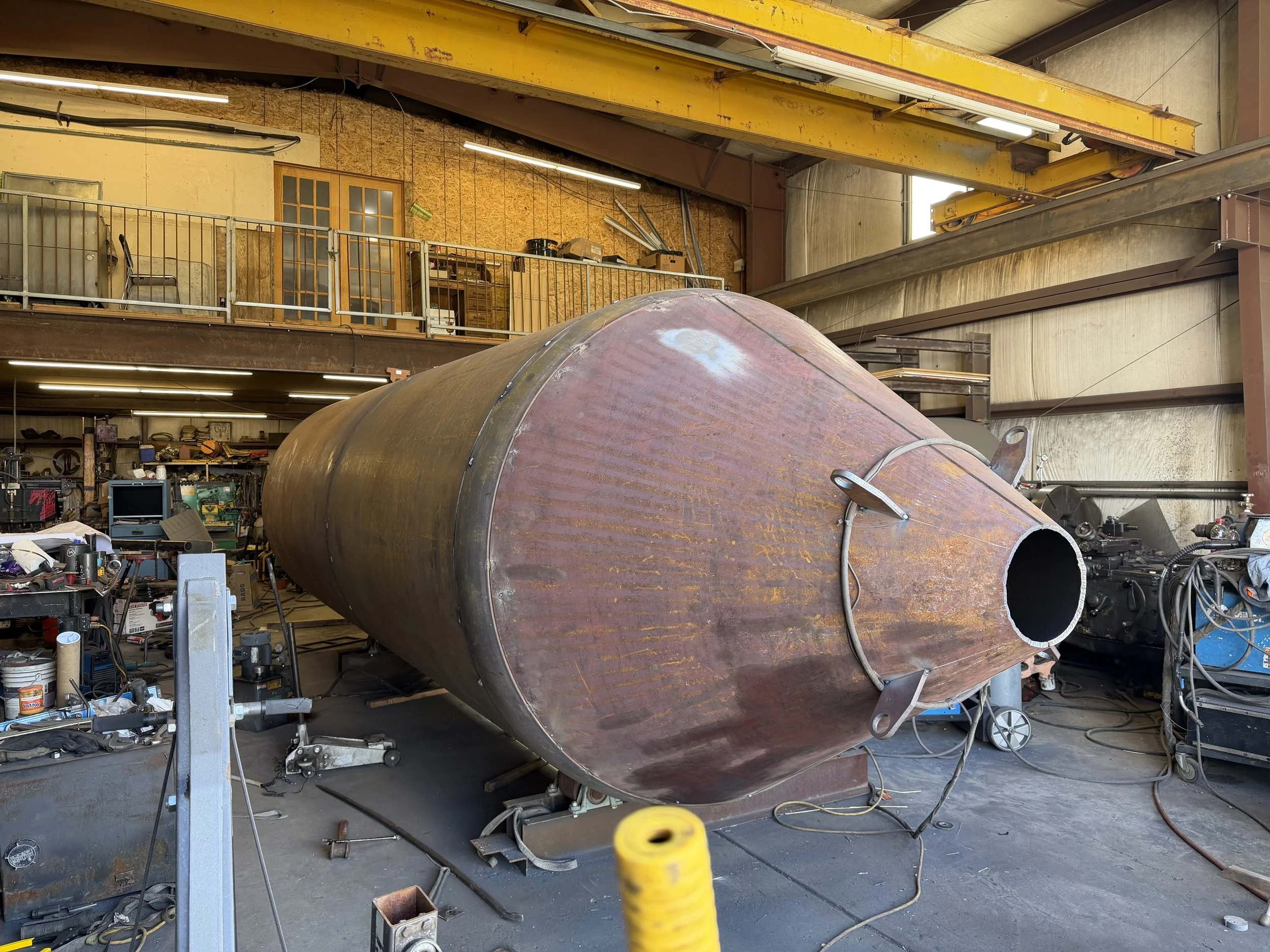 A large custom carbon steel pressure vessel with a conical head undergoing fabrication inside the Peak Welding ASME U-Stamp certified shop in Utah.