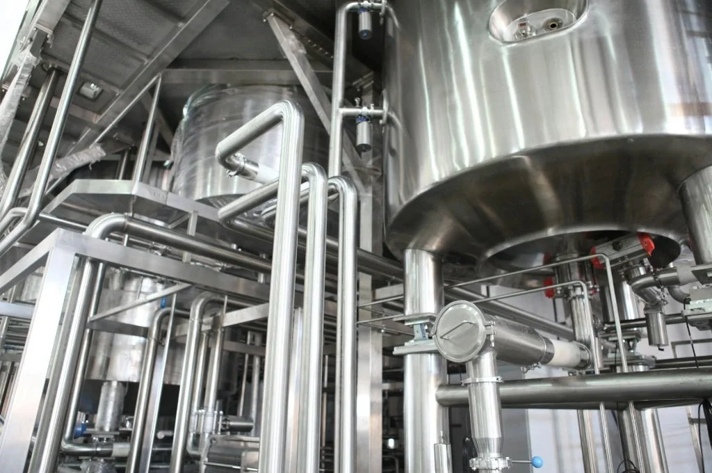 A complex network of polished, high-purity stainless steel sanitary piping and processing vessels fabricated for a food-grade or medical facility.