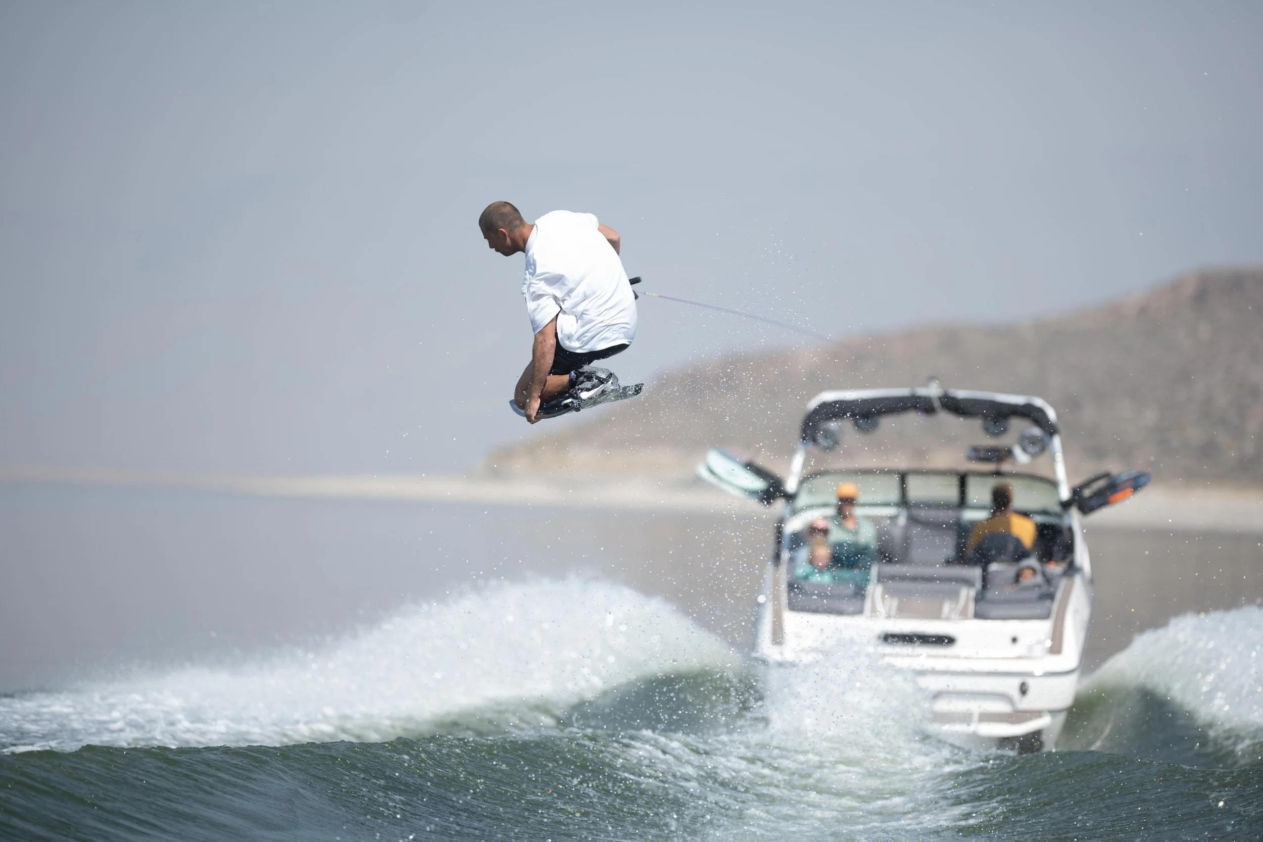 A man wakeboarding on a body of water with a boat in the background.