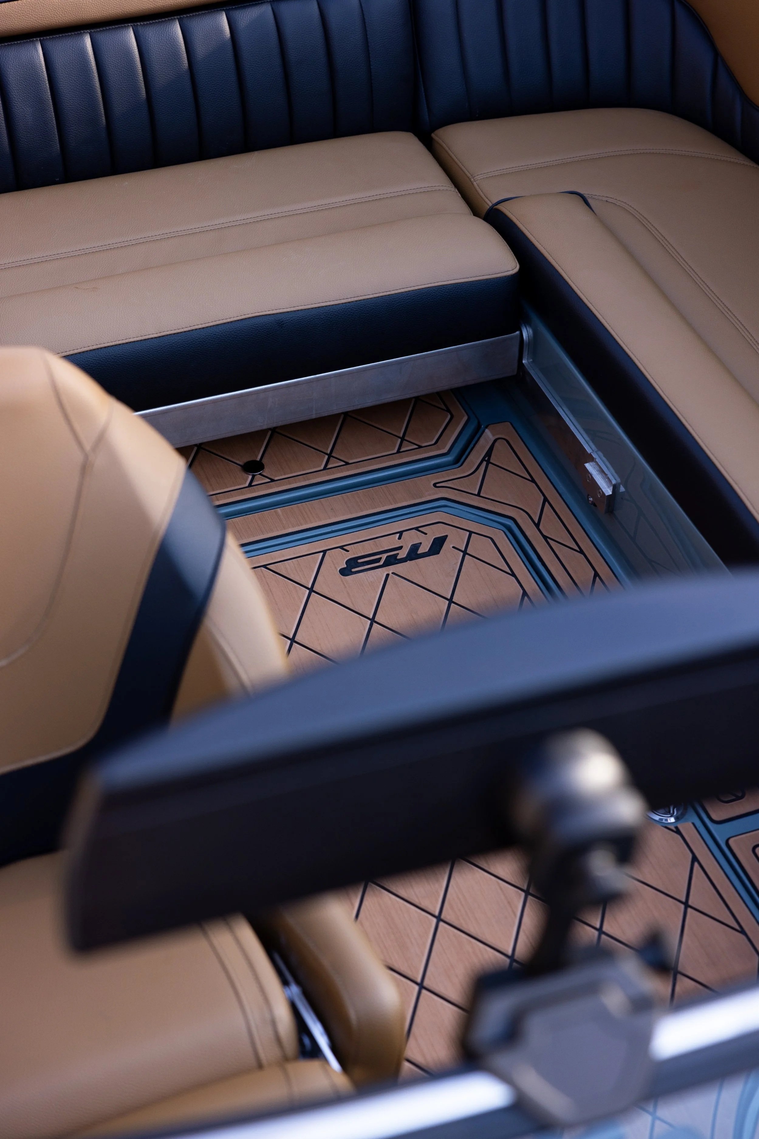 Interior of a vehicle with tan and blue seats and a custom floor mat with a geometric design and the letters "NR".