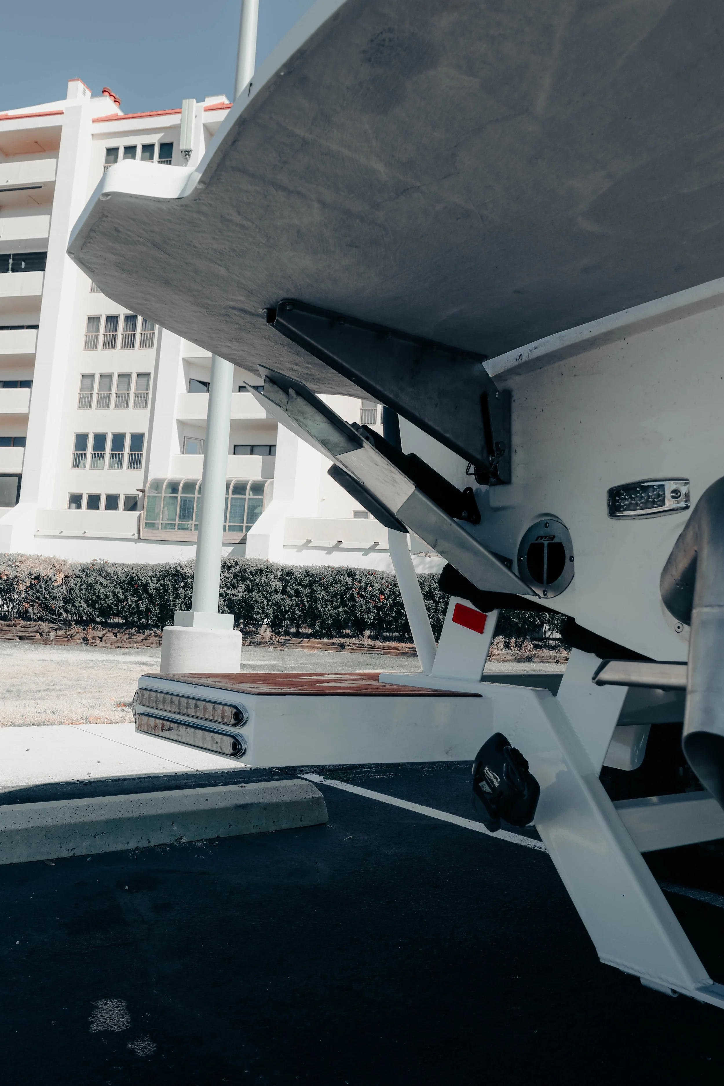 Close-up of a boat lift on a parking lot with apartment building in the background.