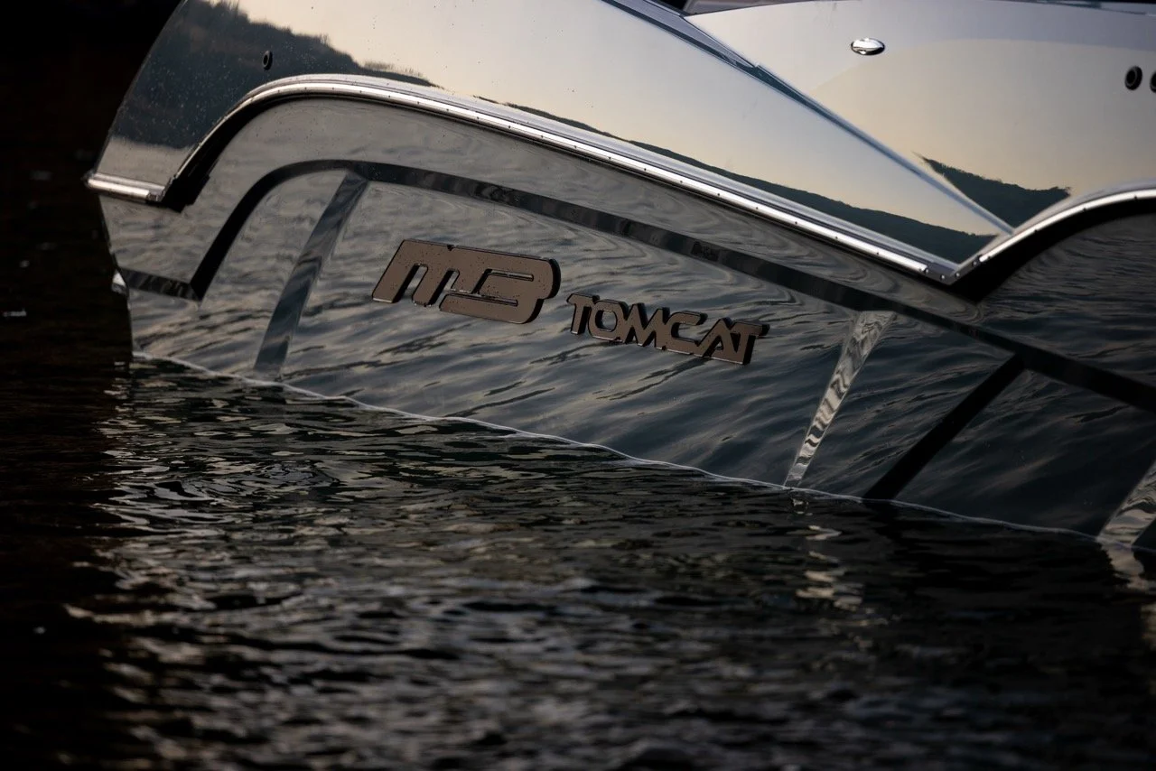 Close-up of the stern of a boat on water, displaying the model name 'TOWCN' and a logo 'MR' on the back of the boat.