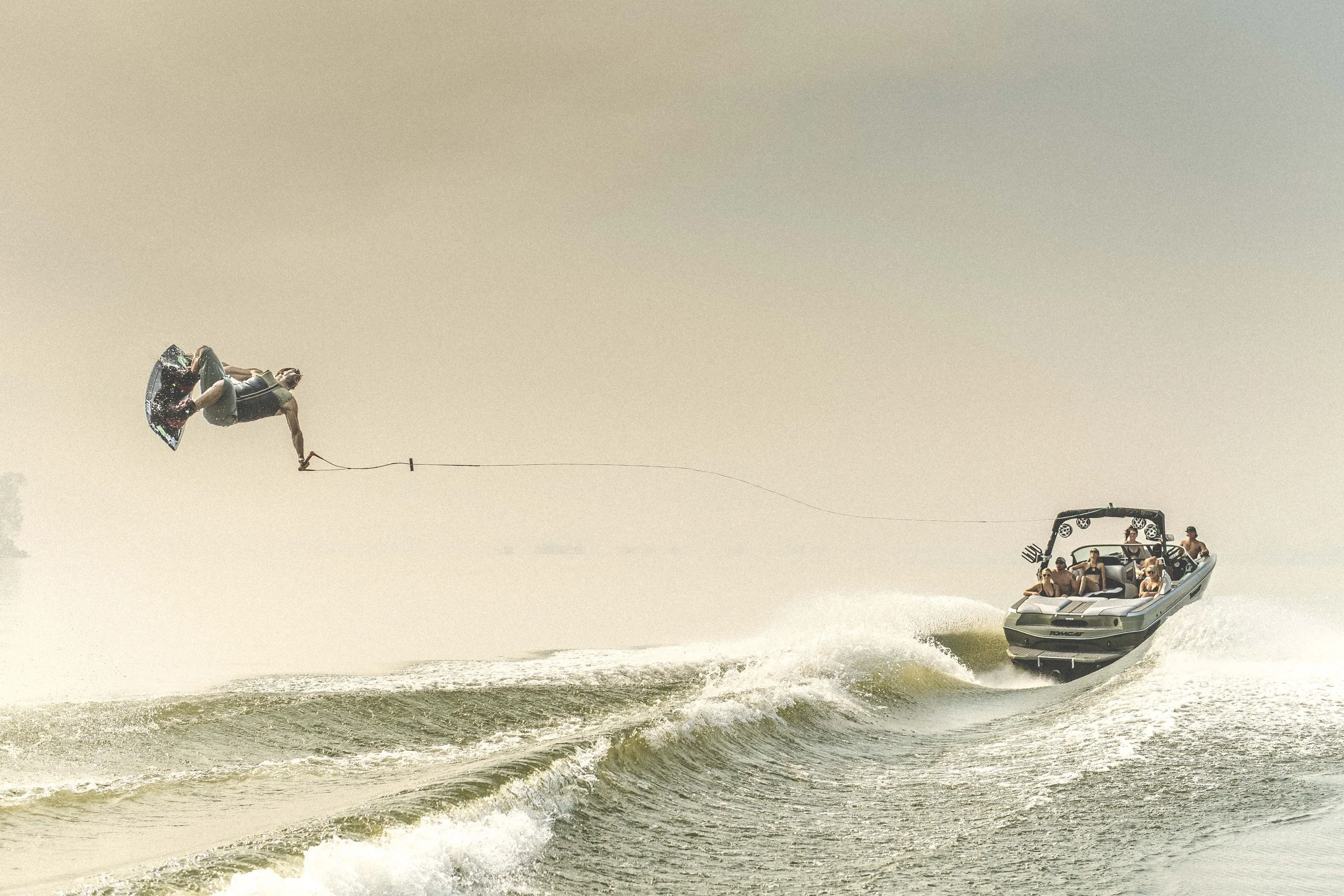 A person being pulled on a wakeboard behind a speedboat on a body of water.
