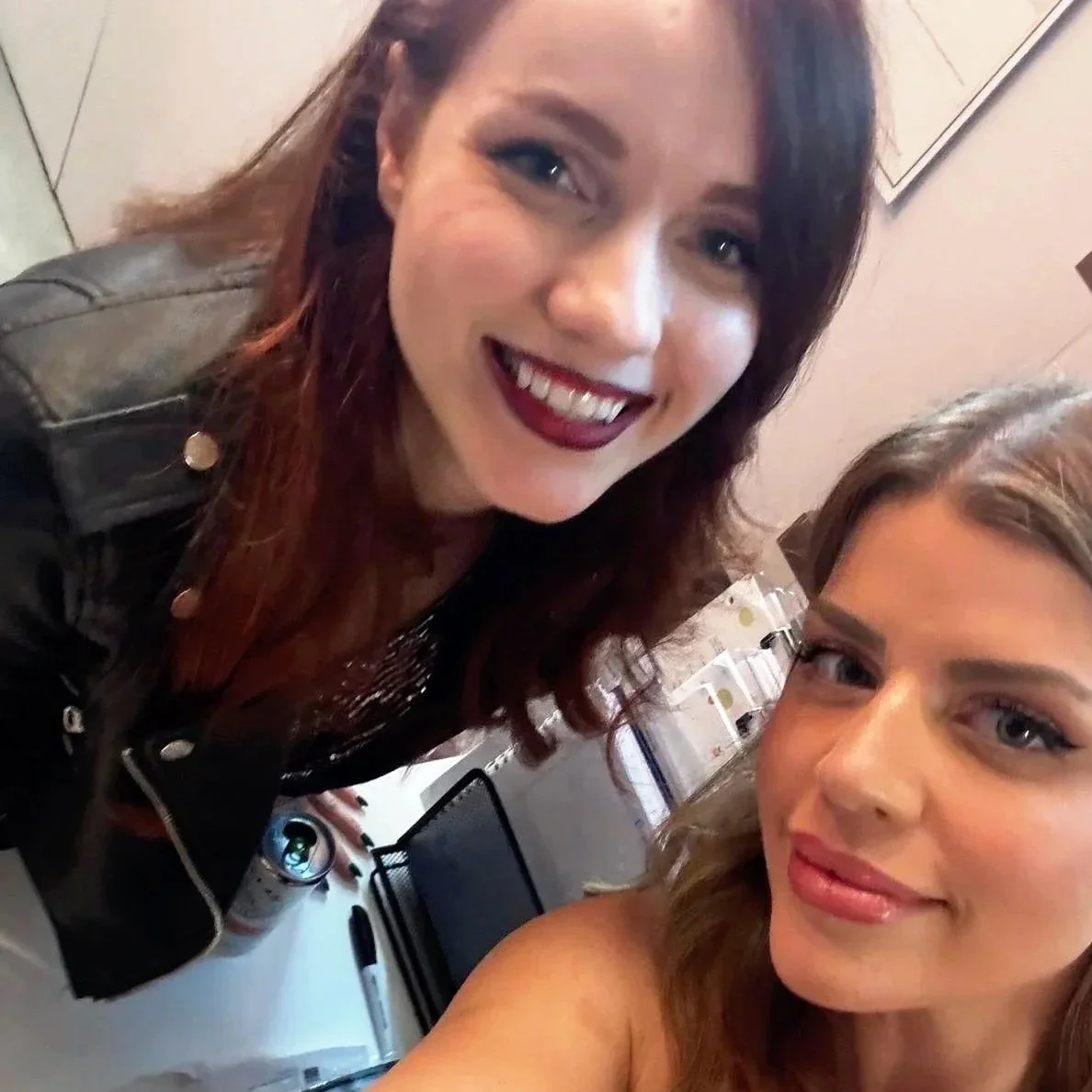 Two women smiling for a selfie in an indoor setting.