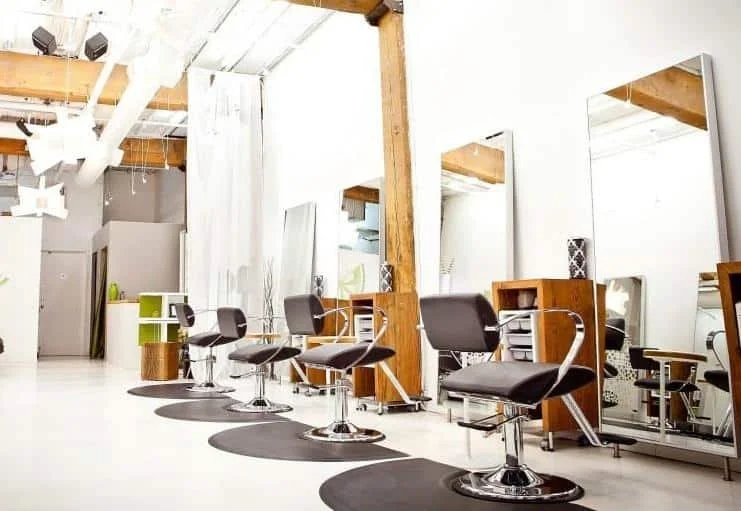 Empty hair salon with chairs, mirrors, and styling stations in a modern, minimalist style.