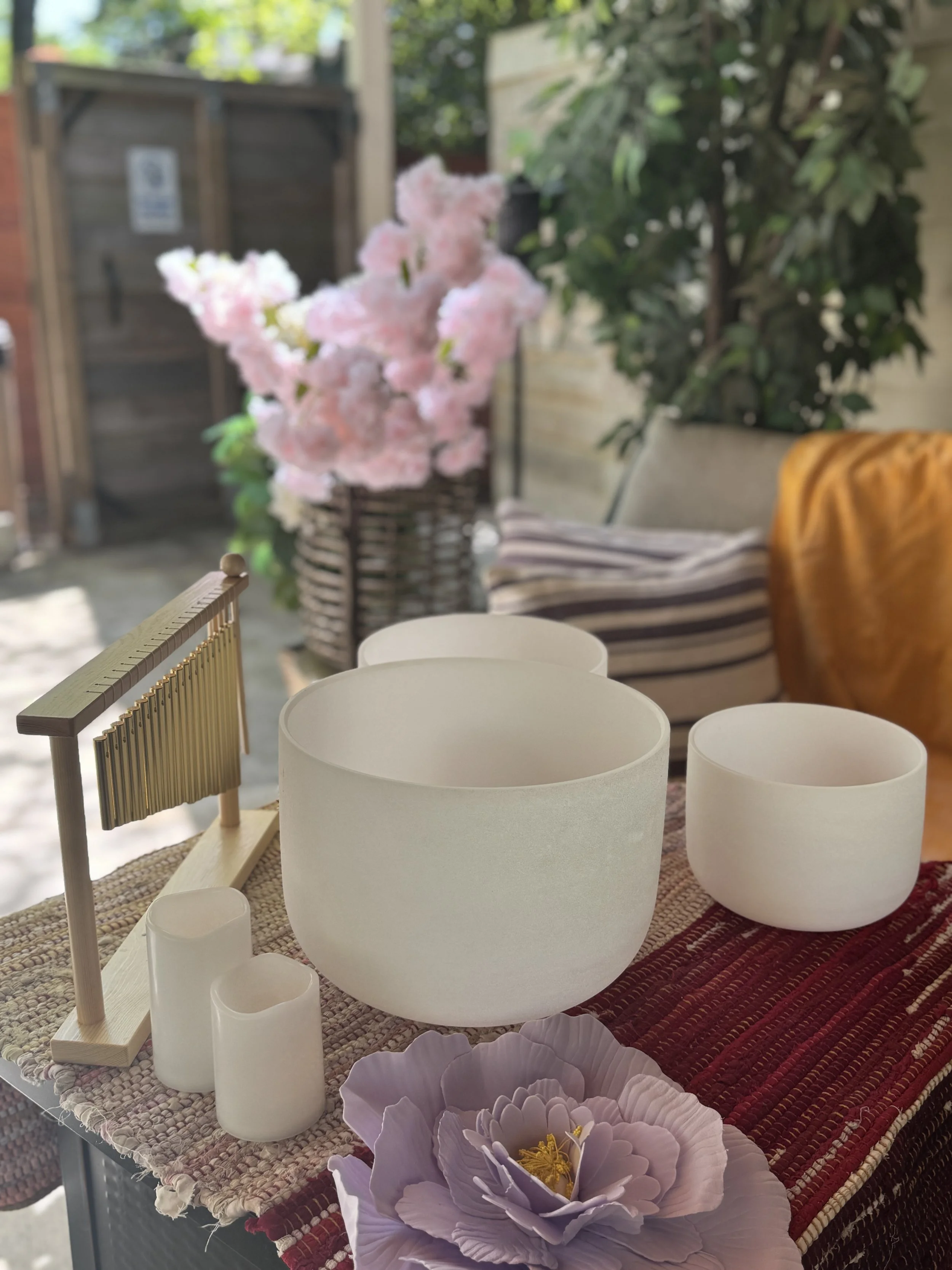 Crystal singing bowls setup for a luxury sound bath experience with candles and chimes in a serene outdoor wellness space in Atlanta