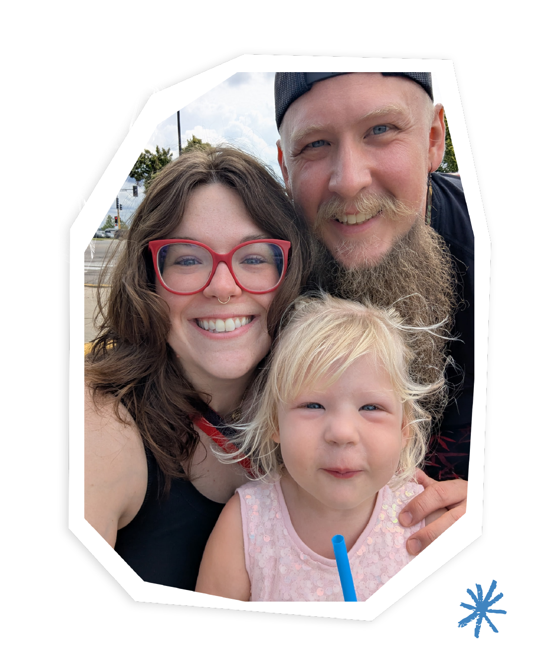 A husband, wife, and their toddler daughter smile at the camera.