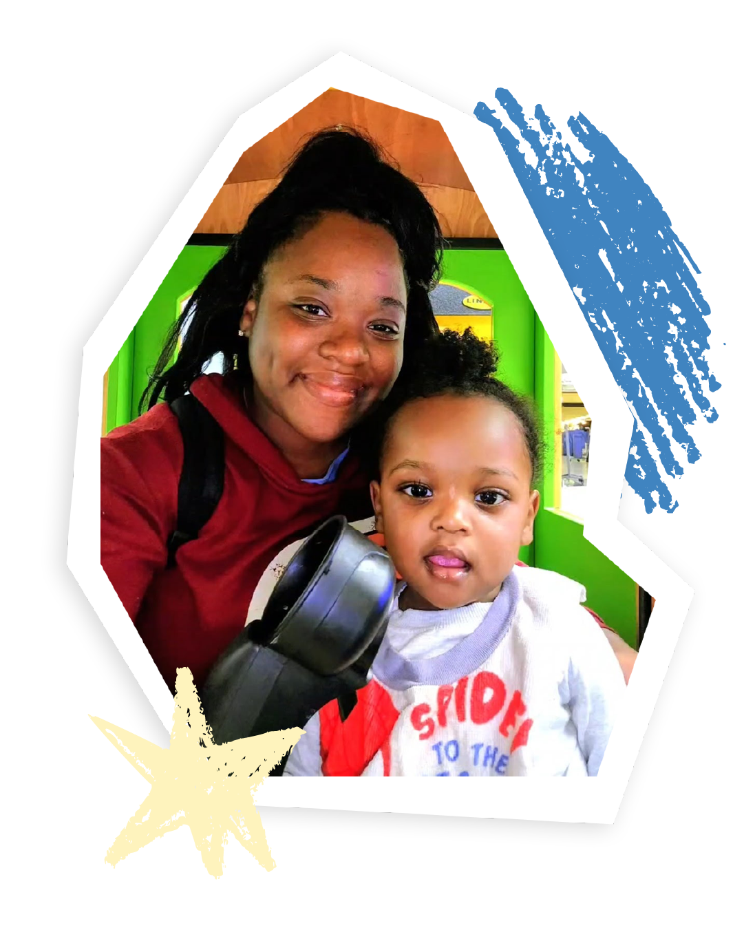 A mother poses for a selfie with her two-year-old son, with a play place in the background.