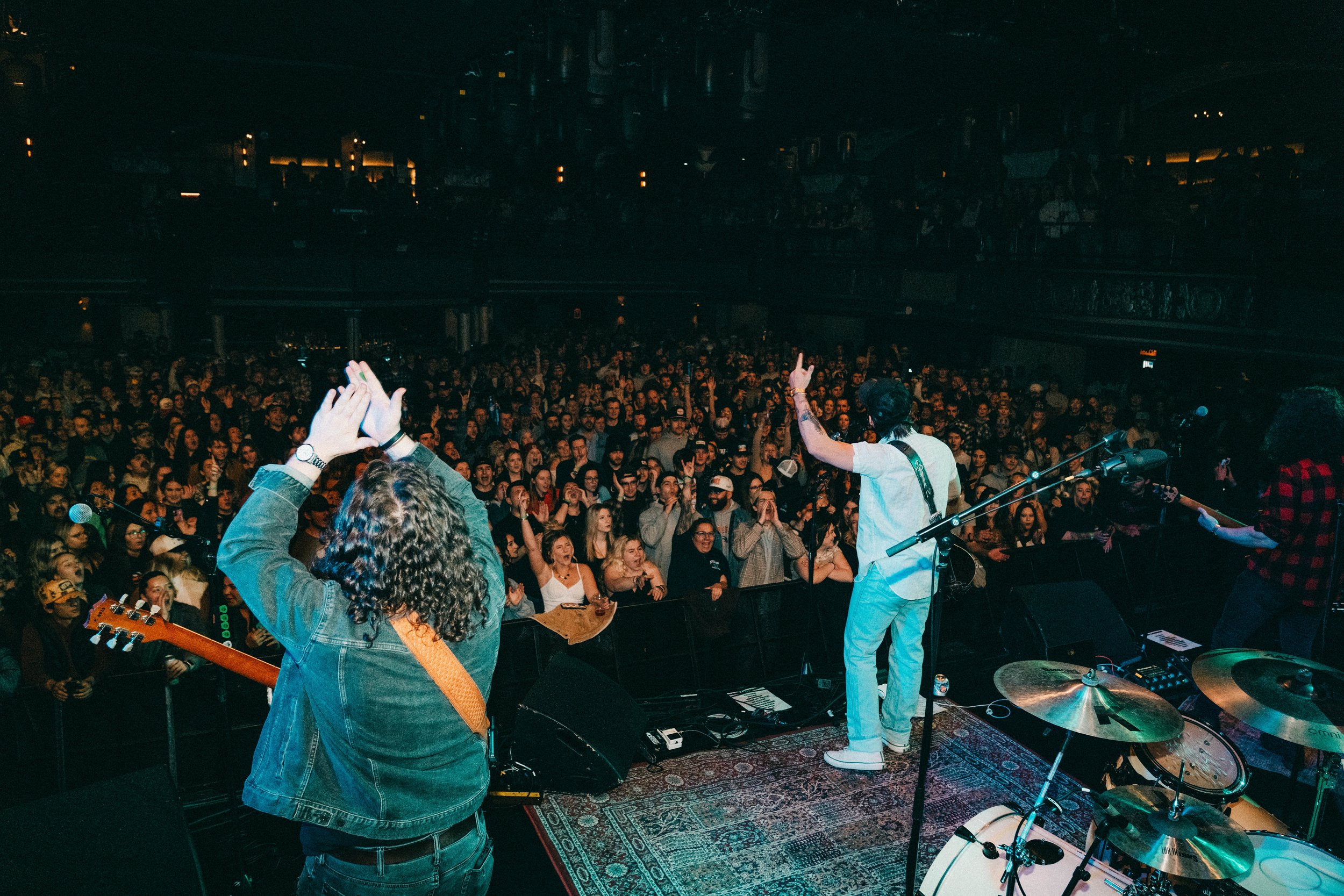 Band playing in front of a large indoor crowd.
