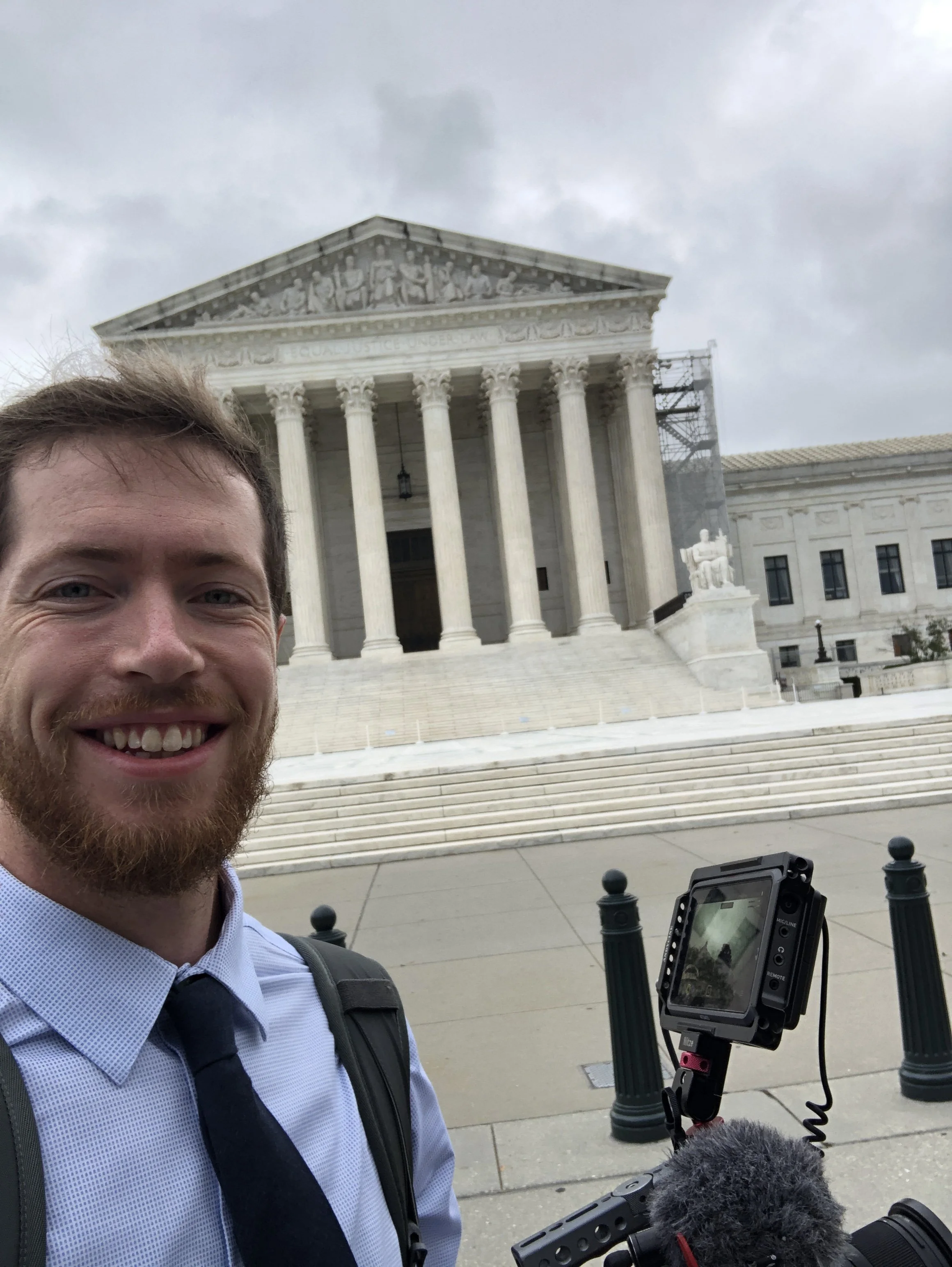 Man with a beard taking a selfie in front of the Jefferson Memorial in Washington, D.C. with a camera mounted on a stabilizer.