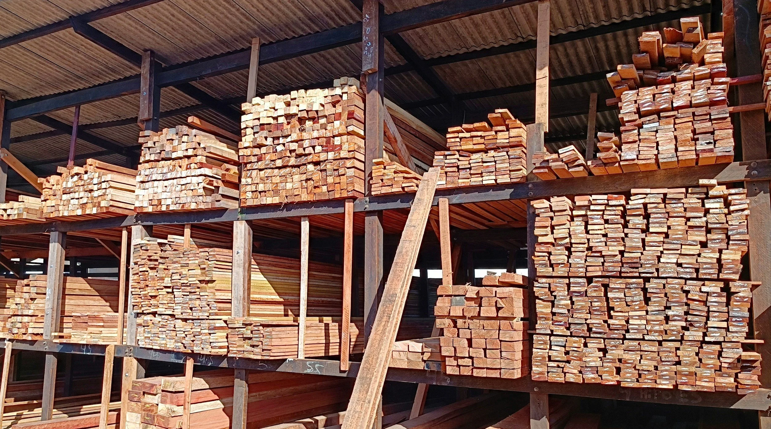 Stacks of wooden planks stored on metal racks in a lumber yard