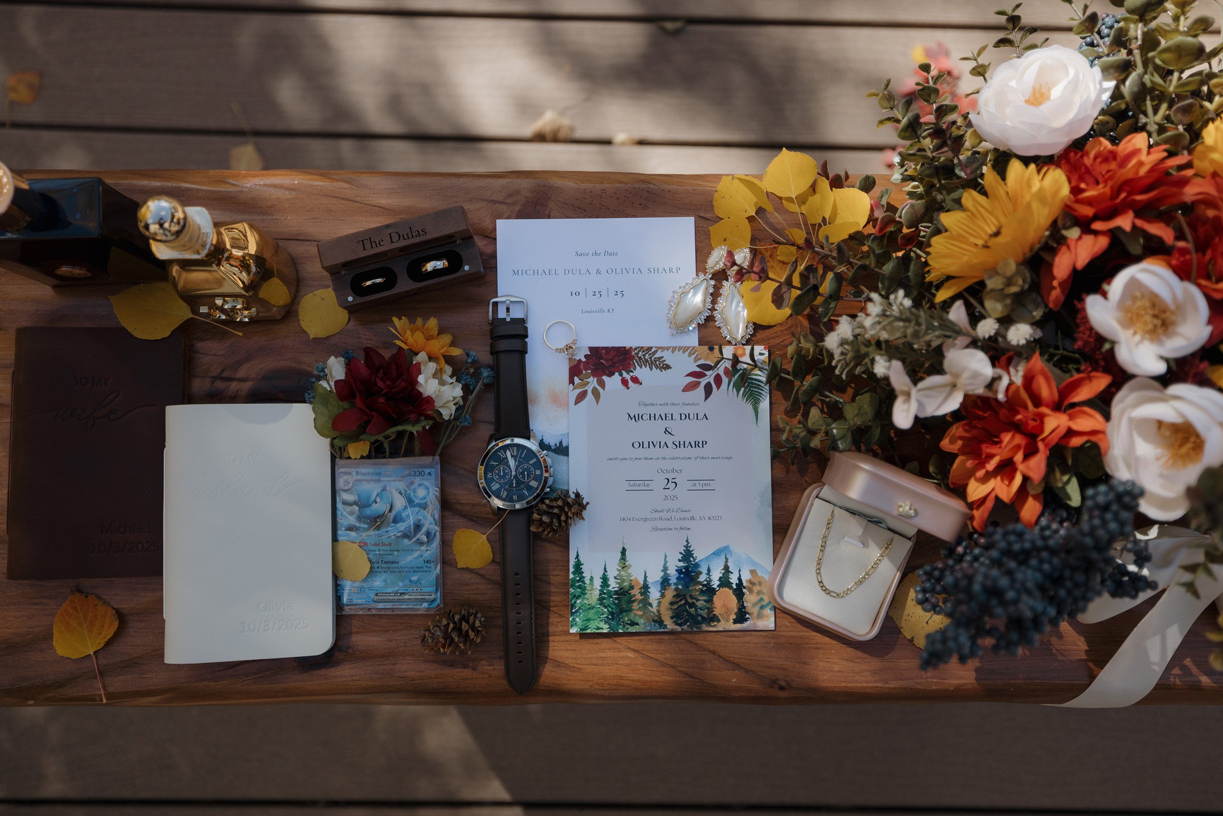 Wedding invitation, jewelry, watch, small bouquet, lottery ticket, and a large bouquet of flowers arranged on a wooden table.}