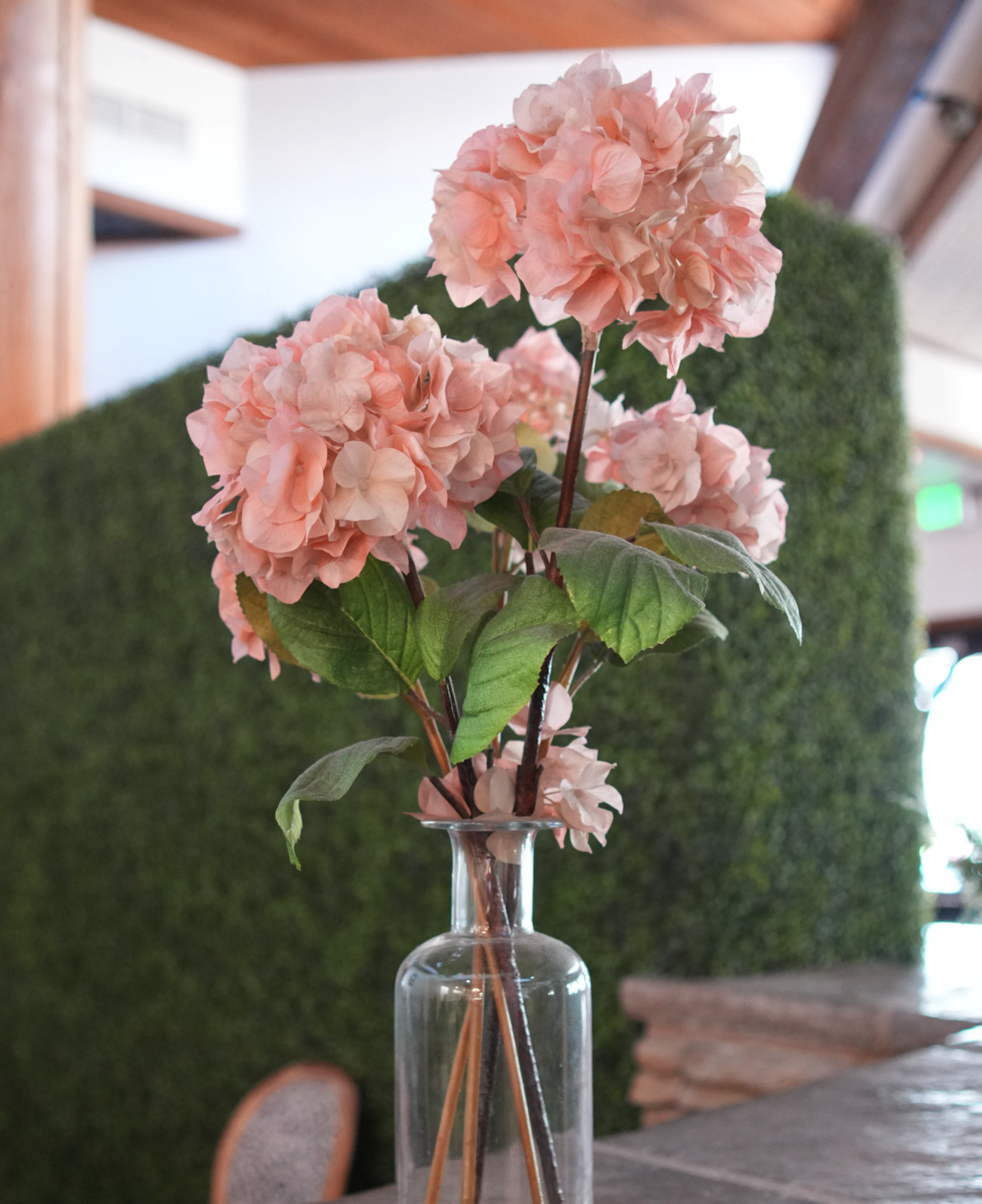 Pink Hydrangea flowers in a clear glass vase on a table.