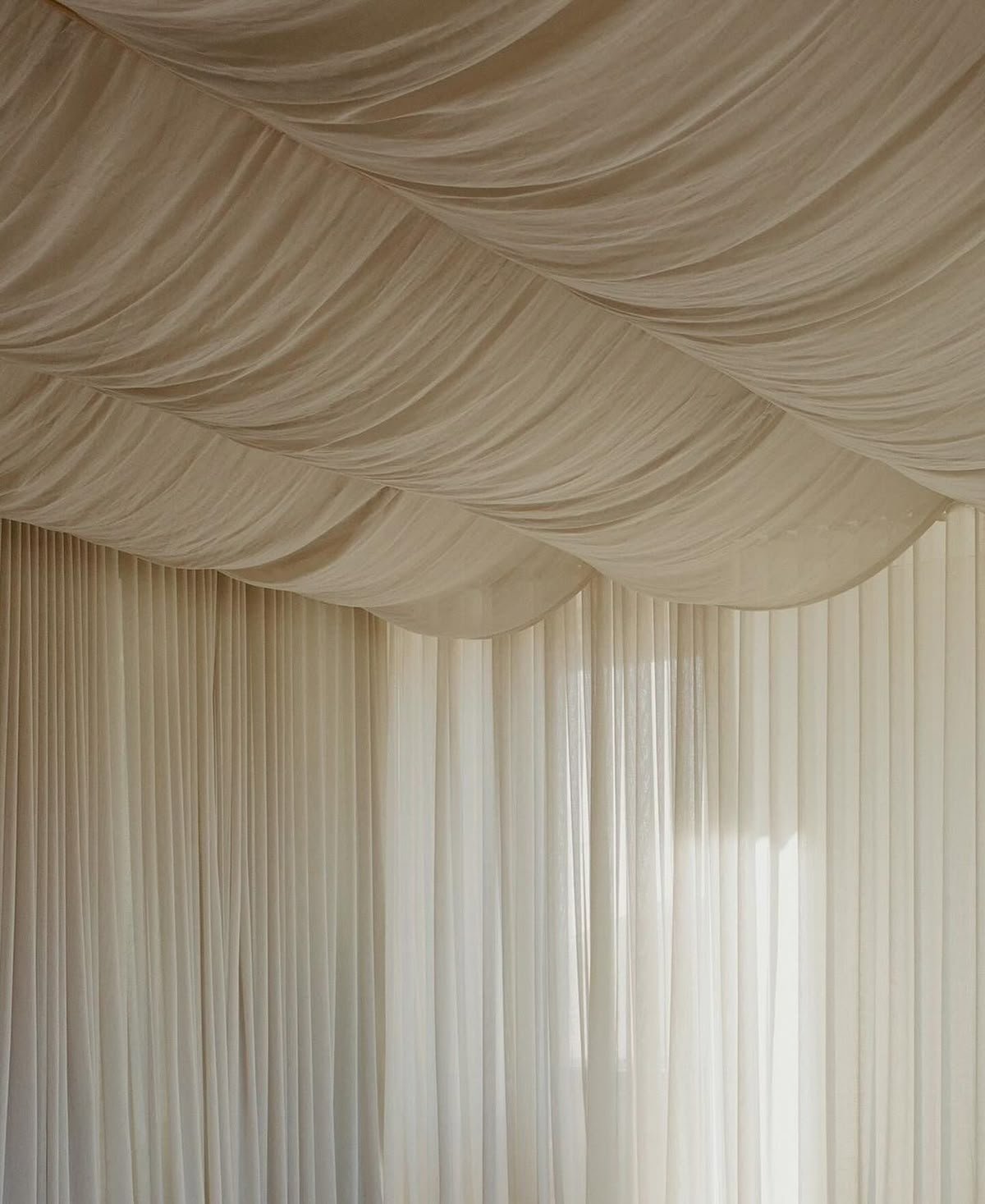 Cream-colored draped curtains and ceiling fabric in an elegant indoor setting.