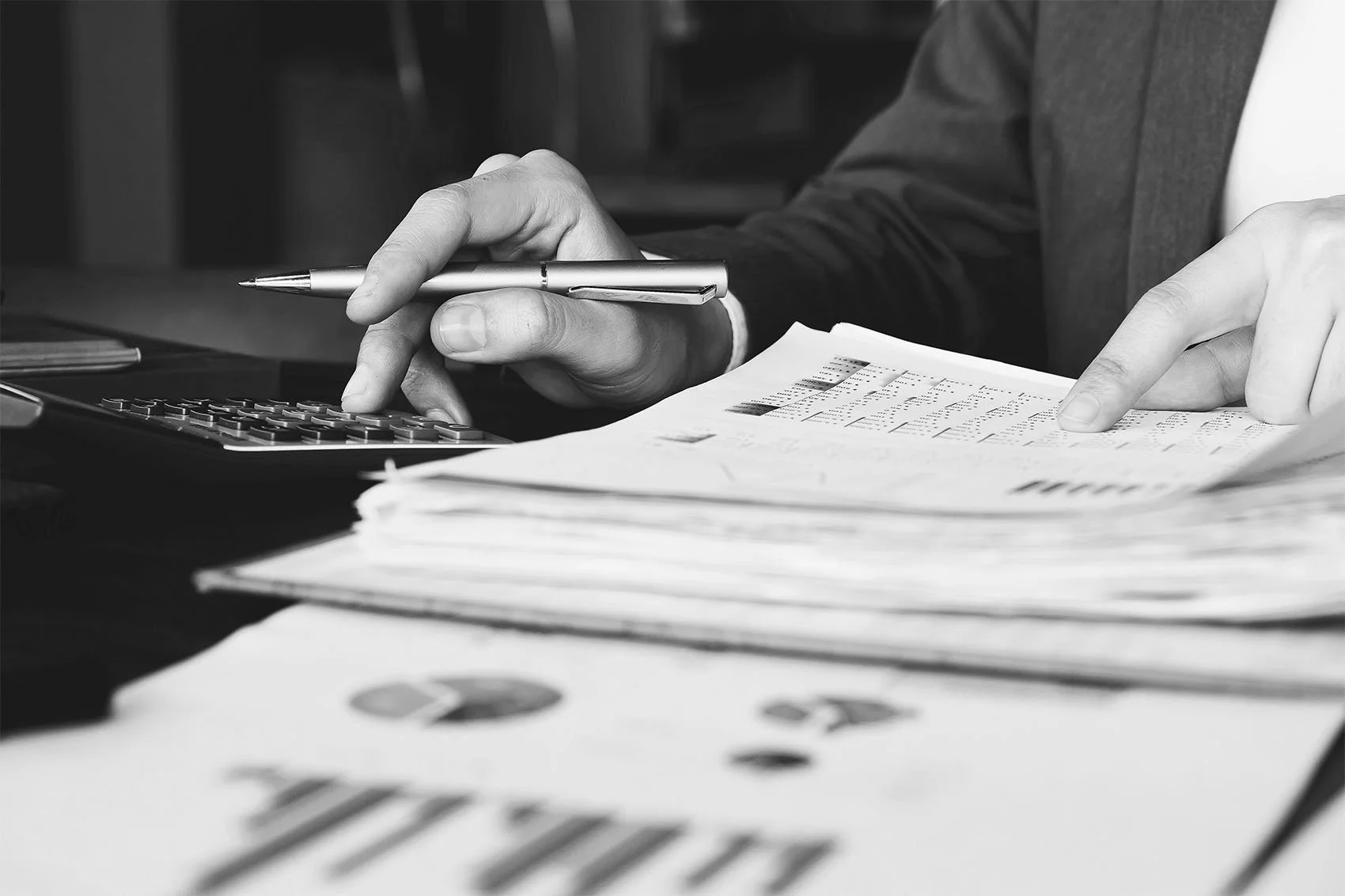 Sales compensation analyst calculating commission payouts and reviewing incentive plan financial documents.