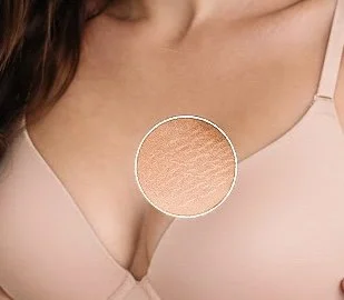 Close-up of a woman's cleavage wearing a light pink top.