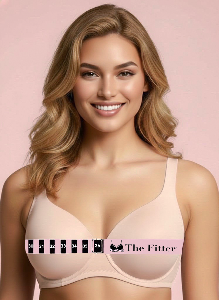 A woman with long, wavy blonde hair smiling, wearing a beige bra and a measuring tape labeled 'The Fitter' across her chest, with the number 36