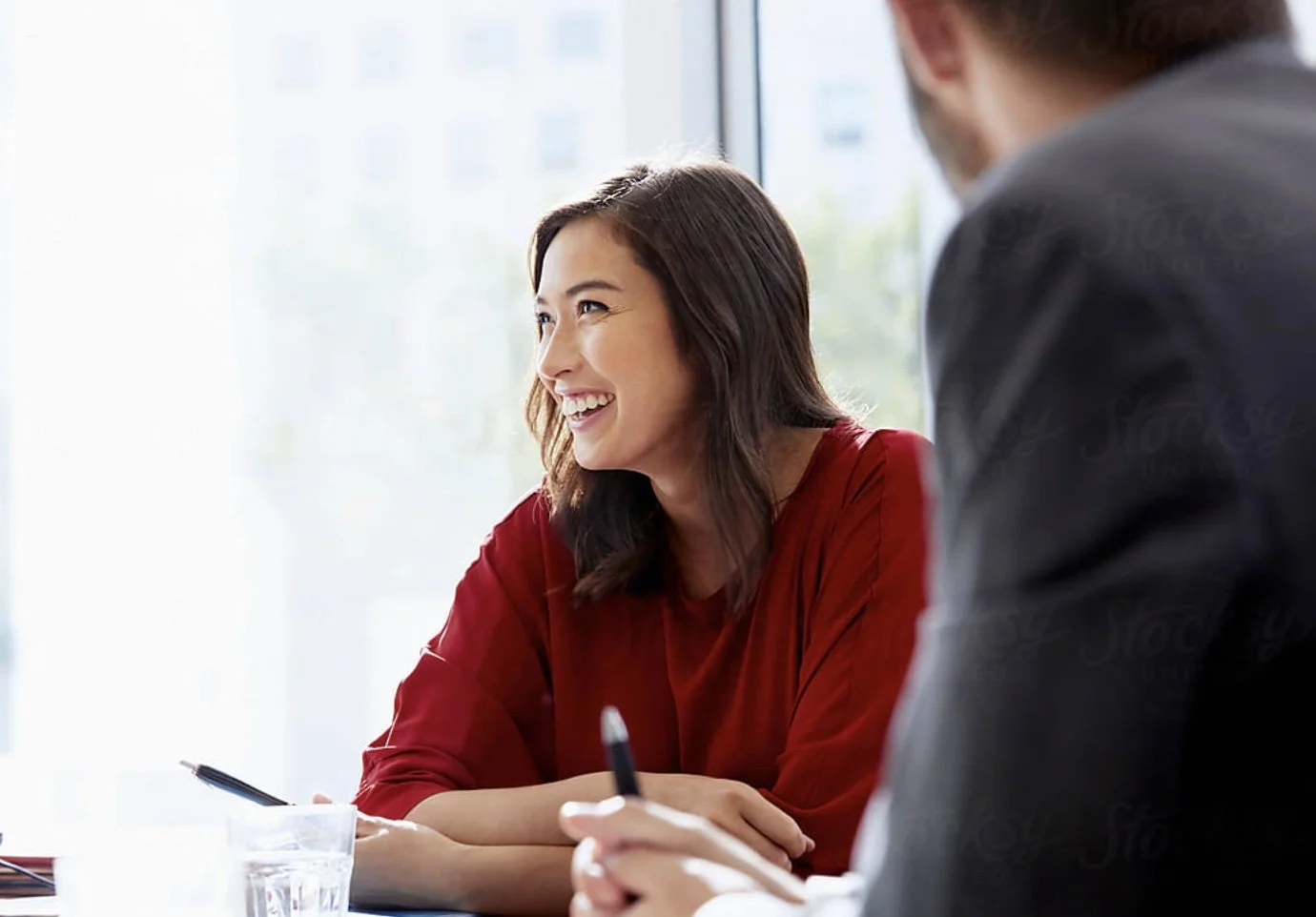 Woman in a red shirt smiling in a leadership coaching engagement