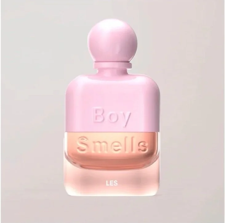 A pink perfume bottle labeled 'Boy Smells LES' with a rounded cap.