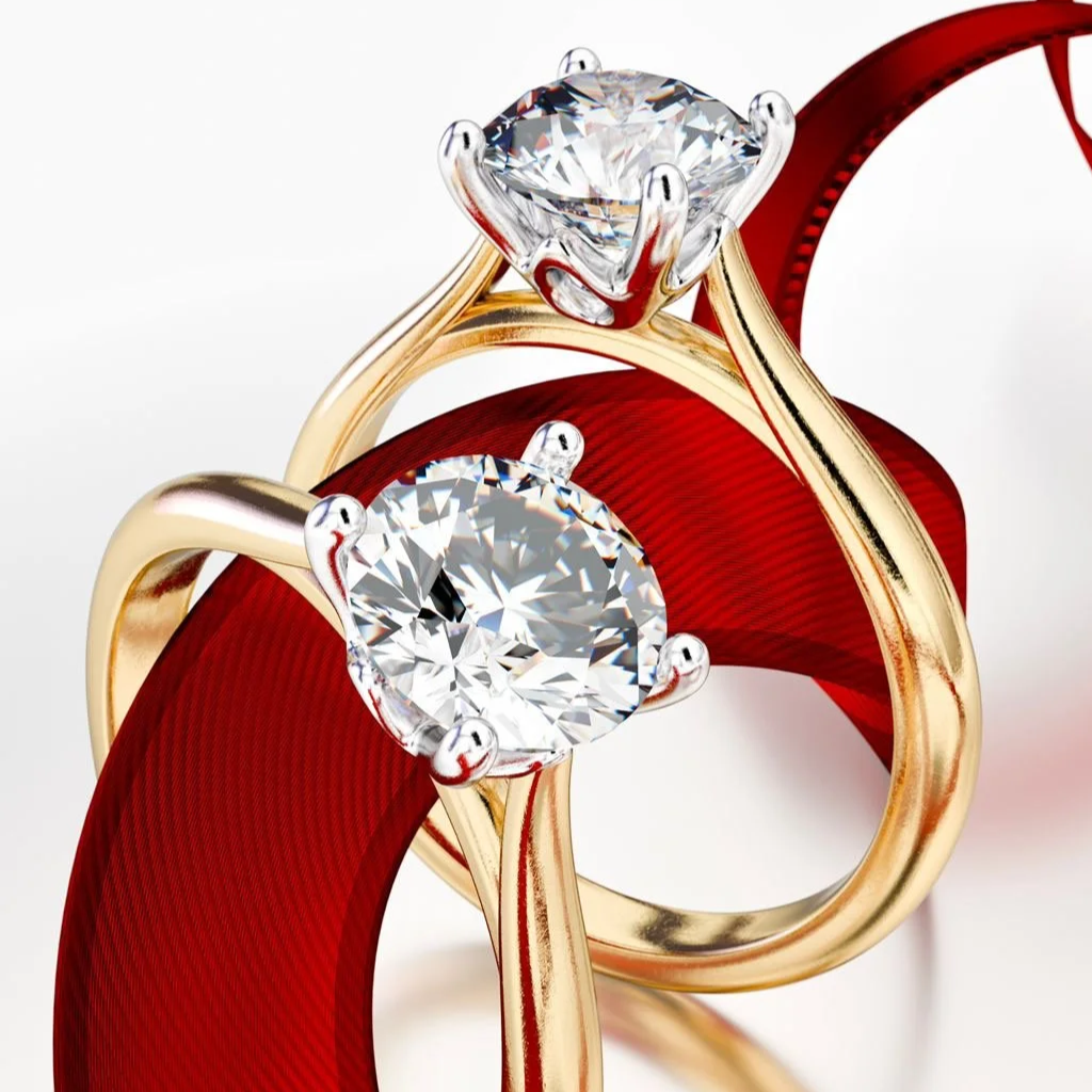 Two gold rings with large, sparkling diamonds, intertwined with a red ribbon.