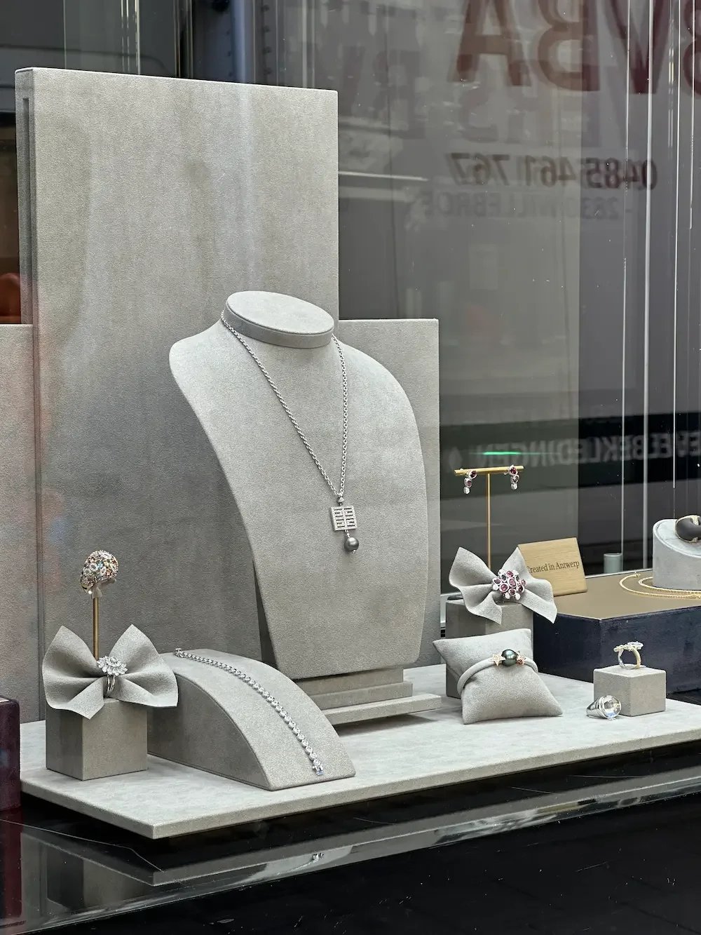 Display of jewelry including necklaces, earrings, rings, and bracelets in a boutique window.