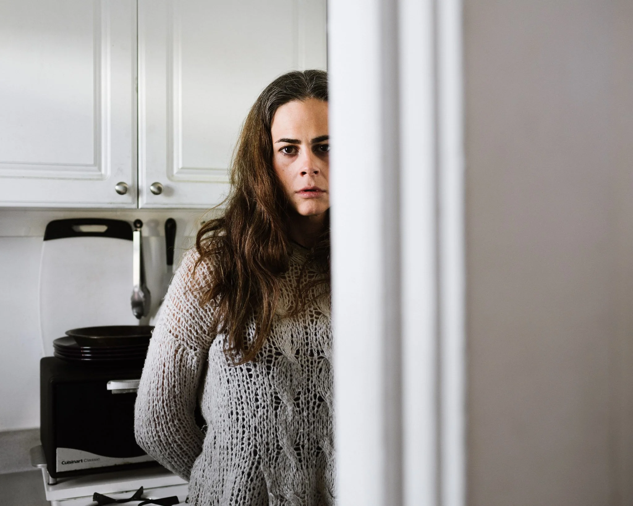 Intimate portrait of a trans woman in her kitchen, her face partially obscured by the wall. The Denver intimate portrait is a metaphor for the sequestered life she has been living, afraid of being in public, of judgement and the violence of men.