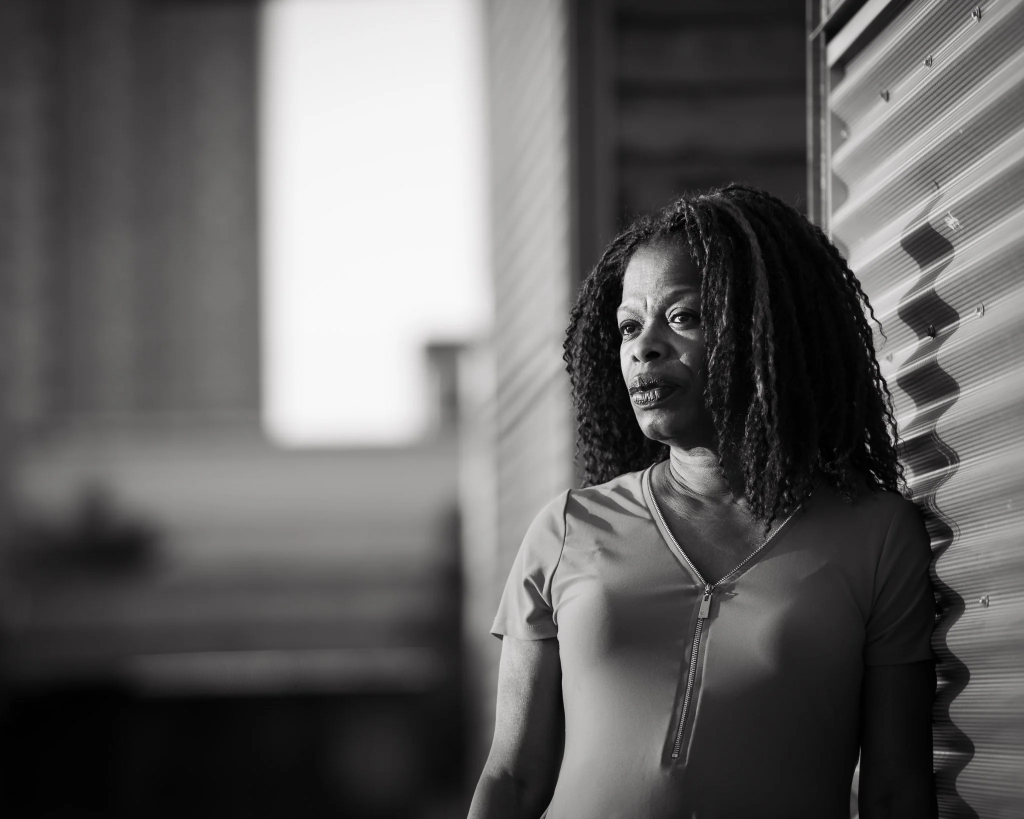 Monochromatic image of African American woman with the defocused city skyline behind her.