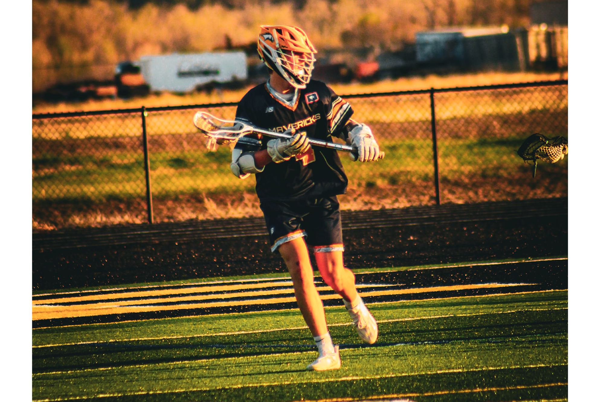 High school lacrosse player with branded helmet and uniform.