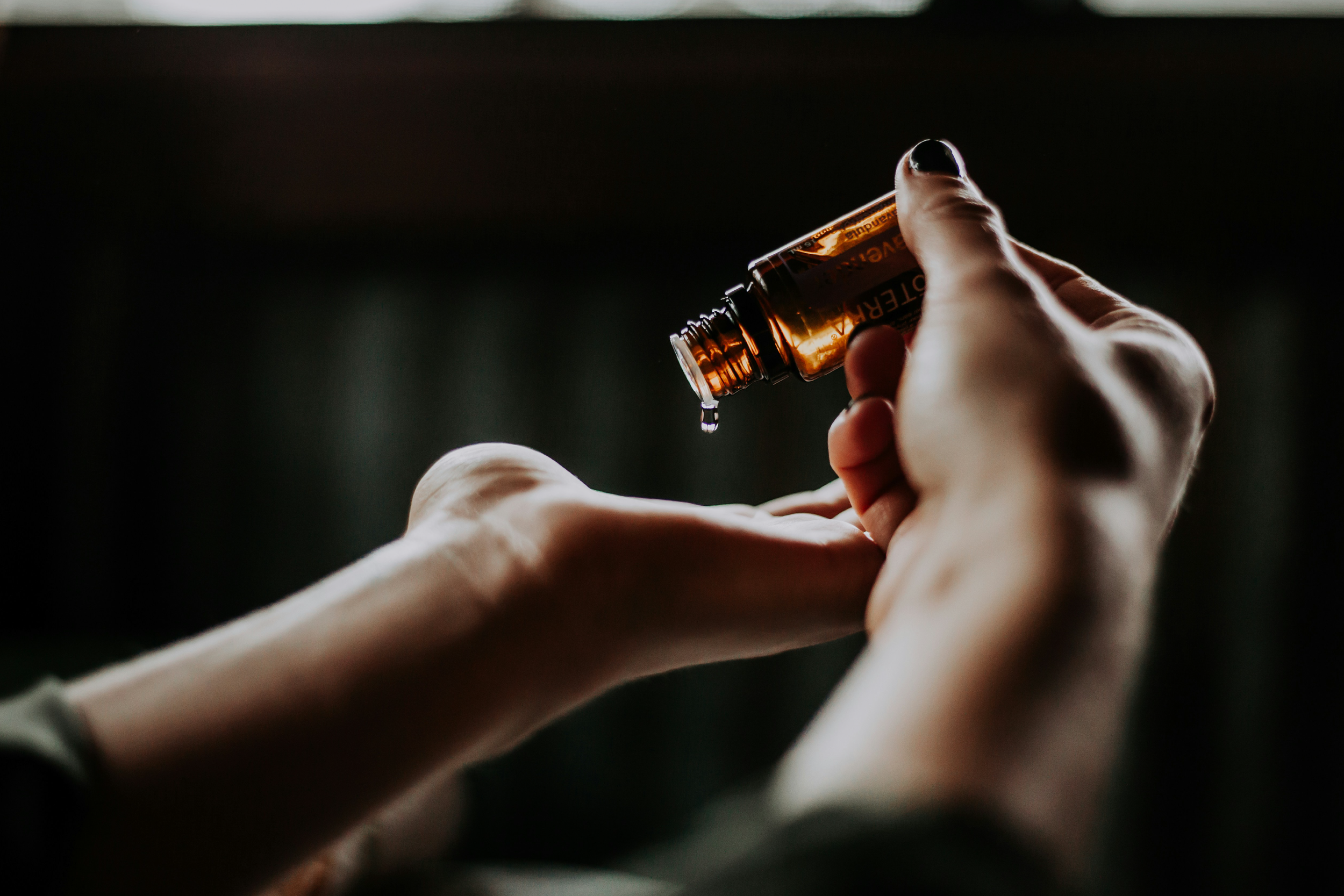 Hands using a bottle of essential oil in a spa setting.