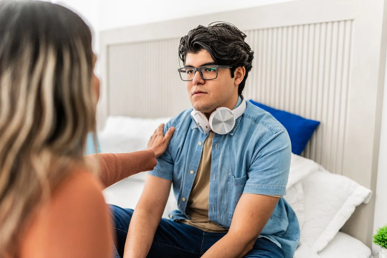 Stressed or frustrated young man with executive function challenges being comforted by mother at home